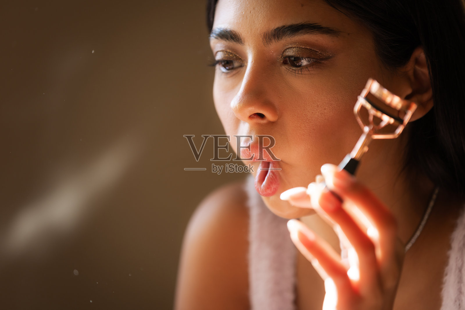 年轻女性正在使用睫毛夹。照片摄影图片