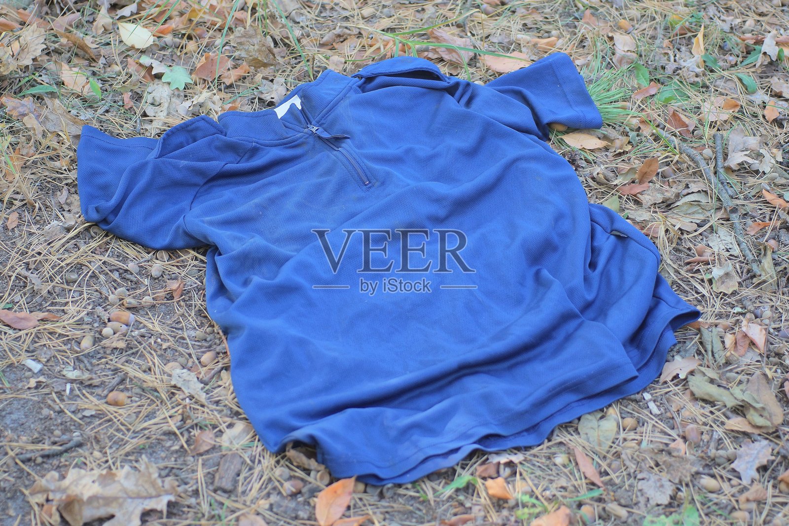 一件蓝色皱巴巴的旧衣服躺在灰色的地面上照片摄影图片