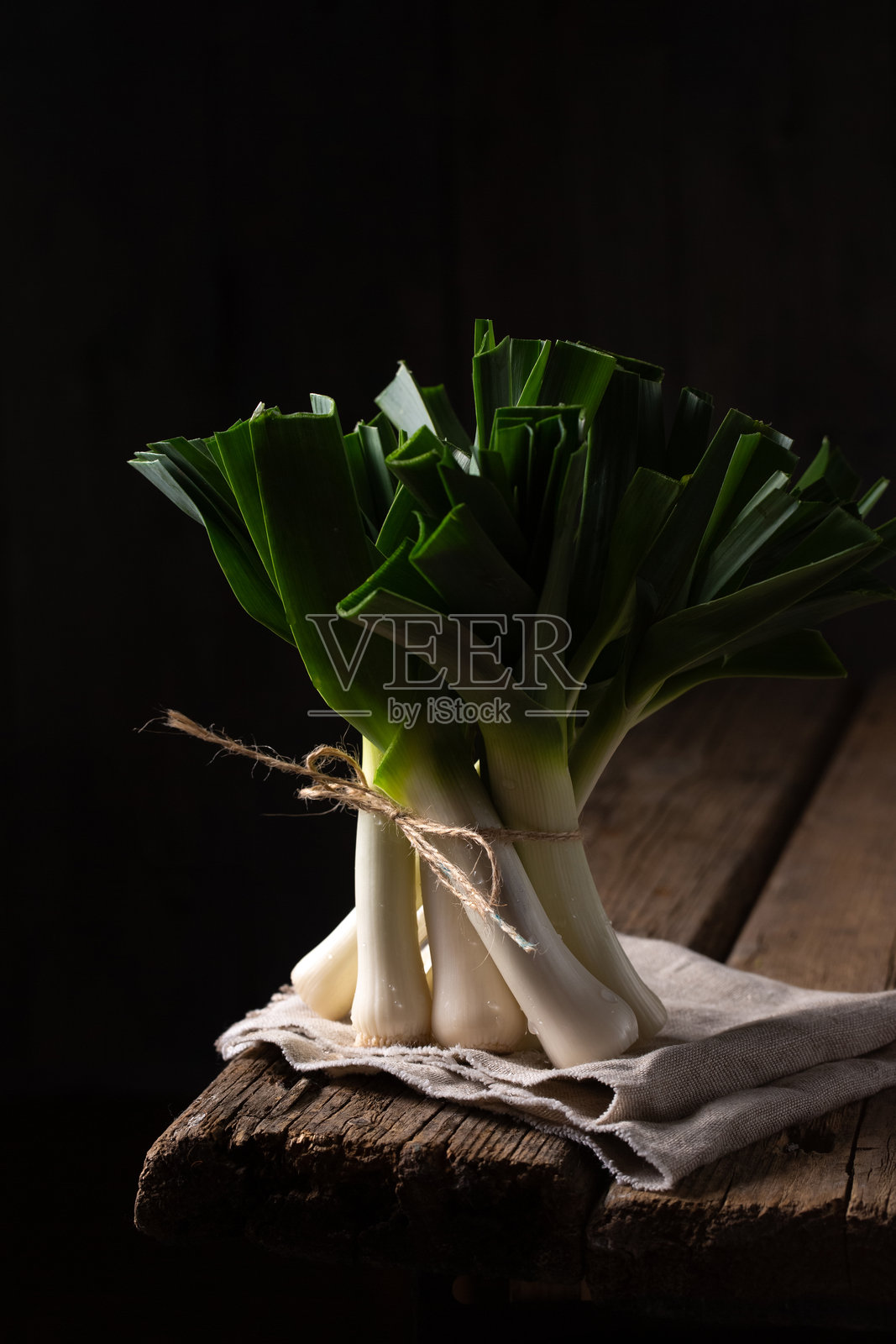一束韭菜放在黑色背景的桌角上照片摄影图片