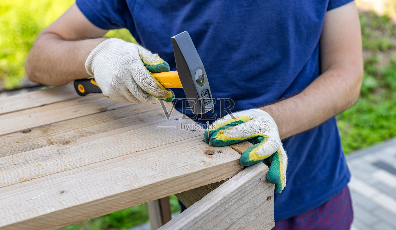 手握锤子将钉子钉入木头。木匠用锤子和钉子修理木板。建筑行业，自助DIY。木工作台。特写。照片摄影图片
