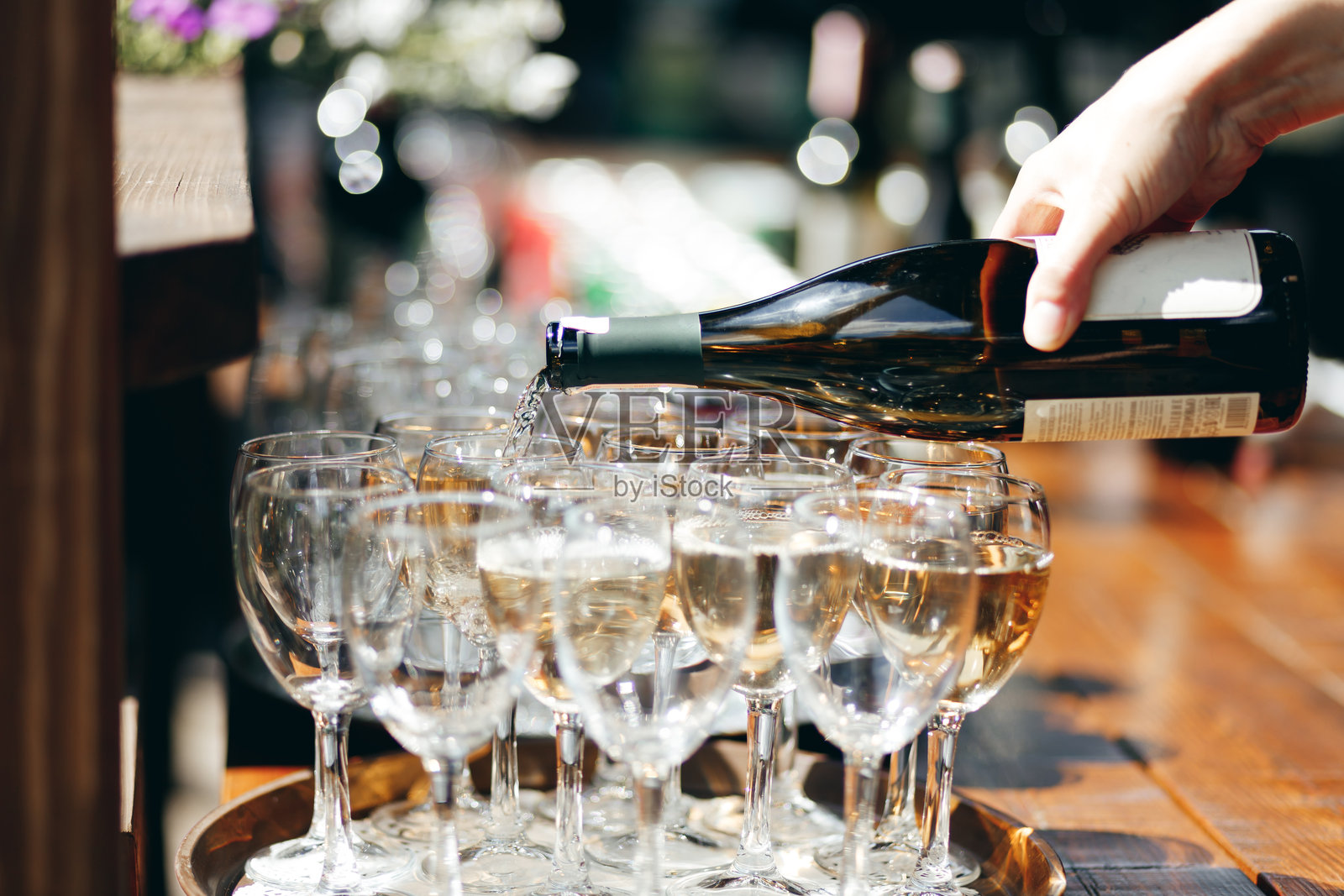 一名服务员在户外自助餐上为酒杯倒酒。照片摄影图片