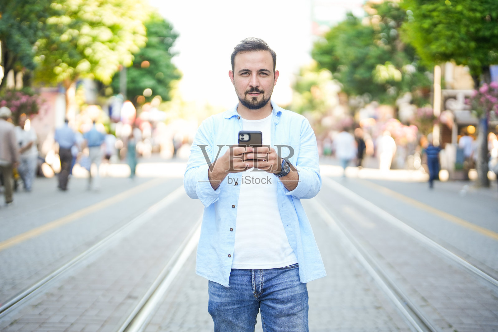 男子在市中心街道上查看手机并进行银行交易照片摄影图片