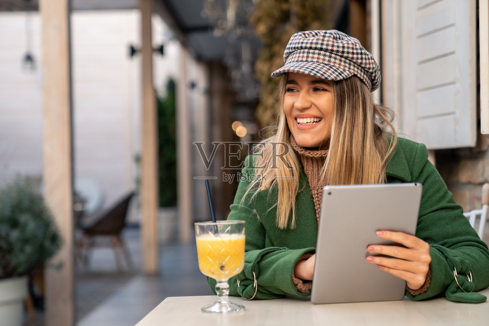 微笑的女性在秋季户外享用温暖饮品，手持平板电脑照片摄影图片