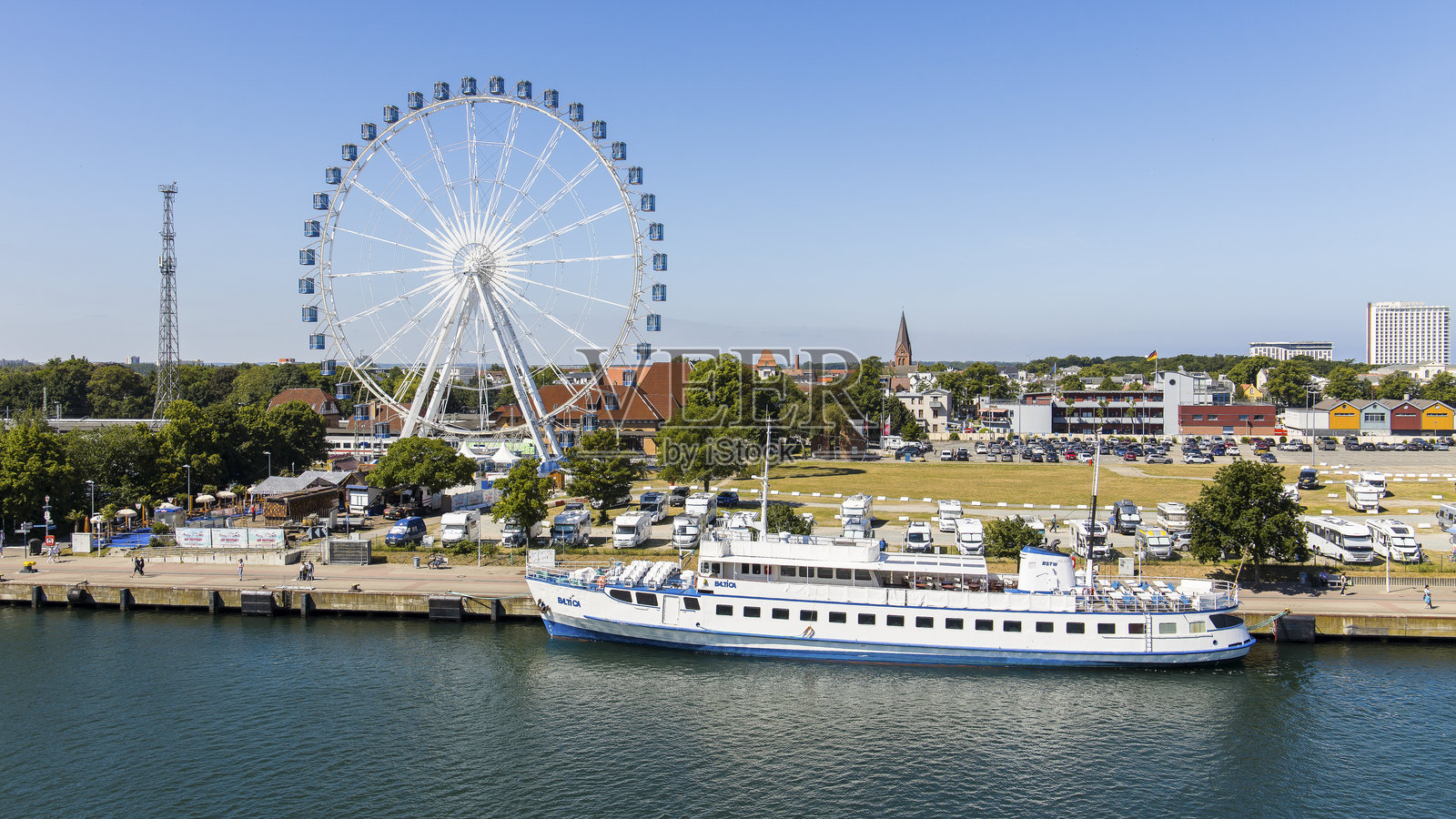 德国罗斯托克的瓦尔内明德港口码头区域，夏日阳光明媚，船只和摩天轮映衬其中。照片摄影图片