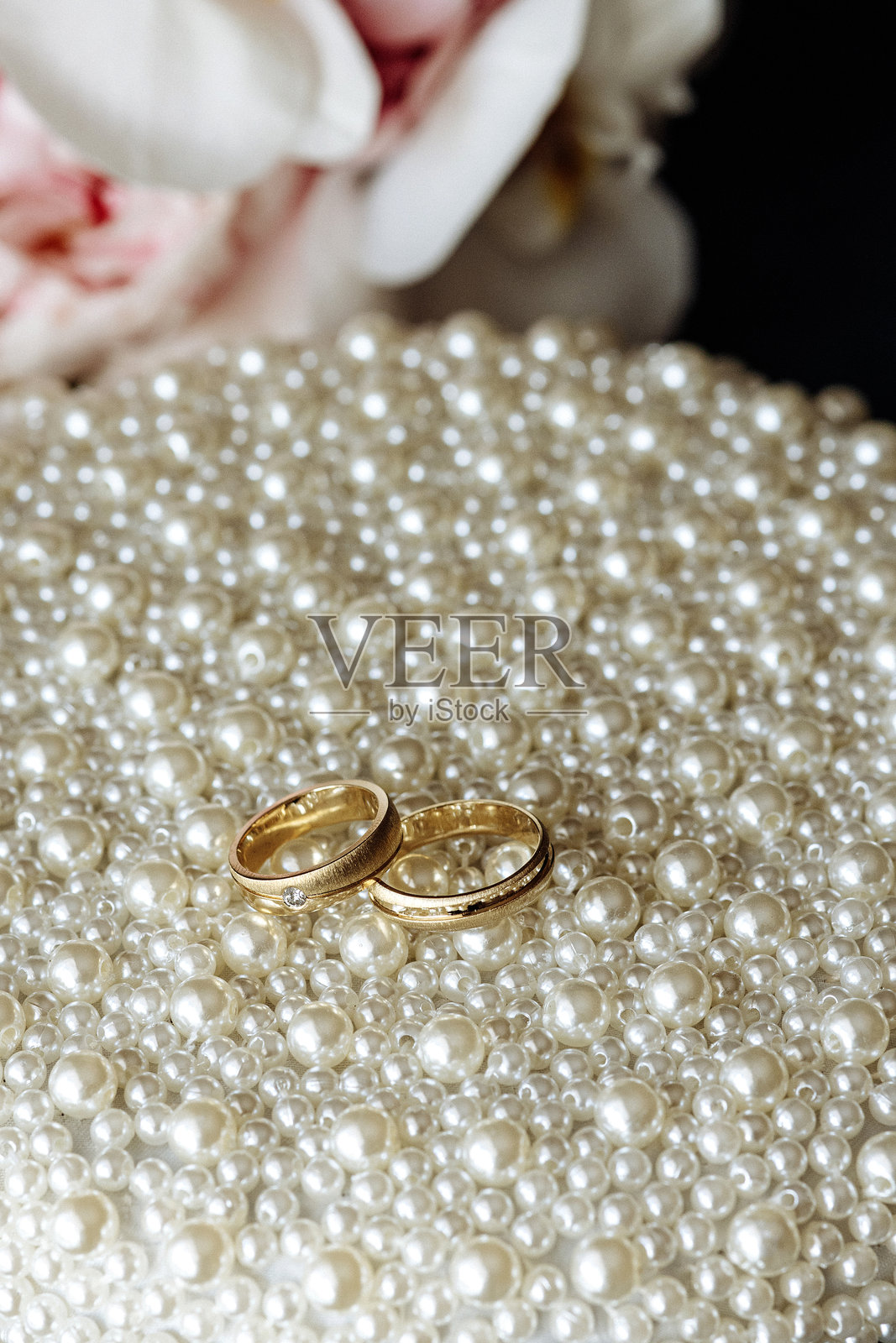 两枚金婚戒放在一床白色珍珠上照片摄影图片