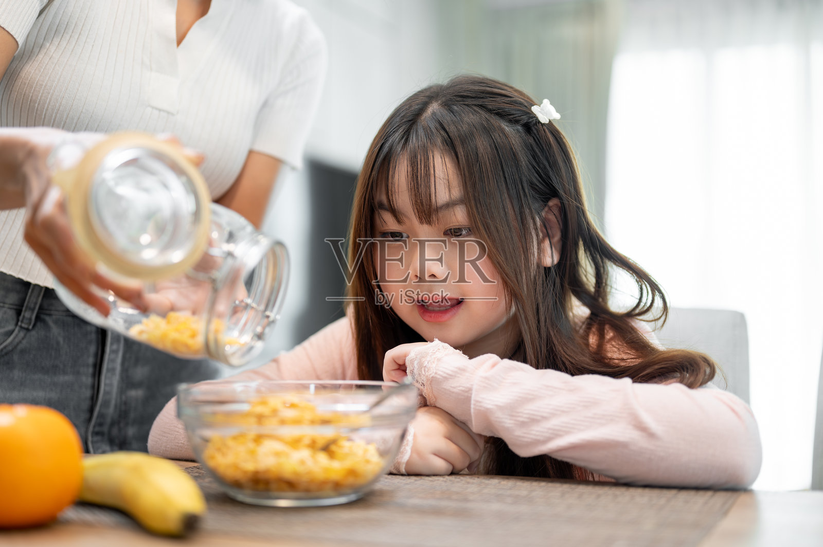 一个年轻可爱的亚洲女孩坐在餐桌旁，兴奋地准备享用她的早餐麦片。照片摄影图片