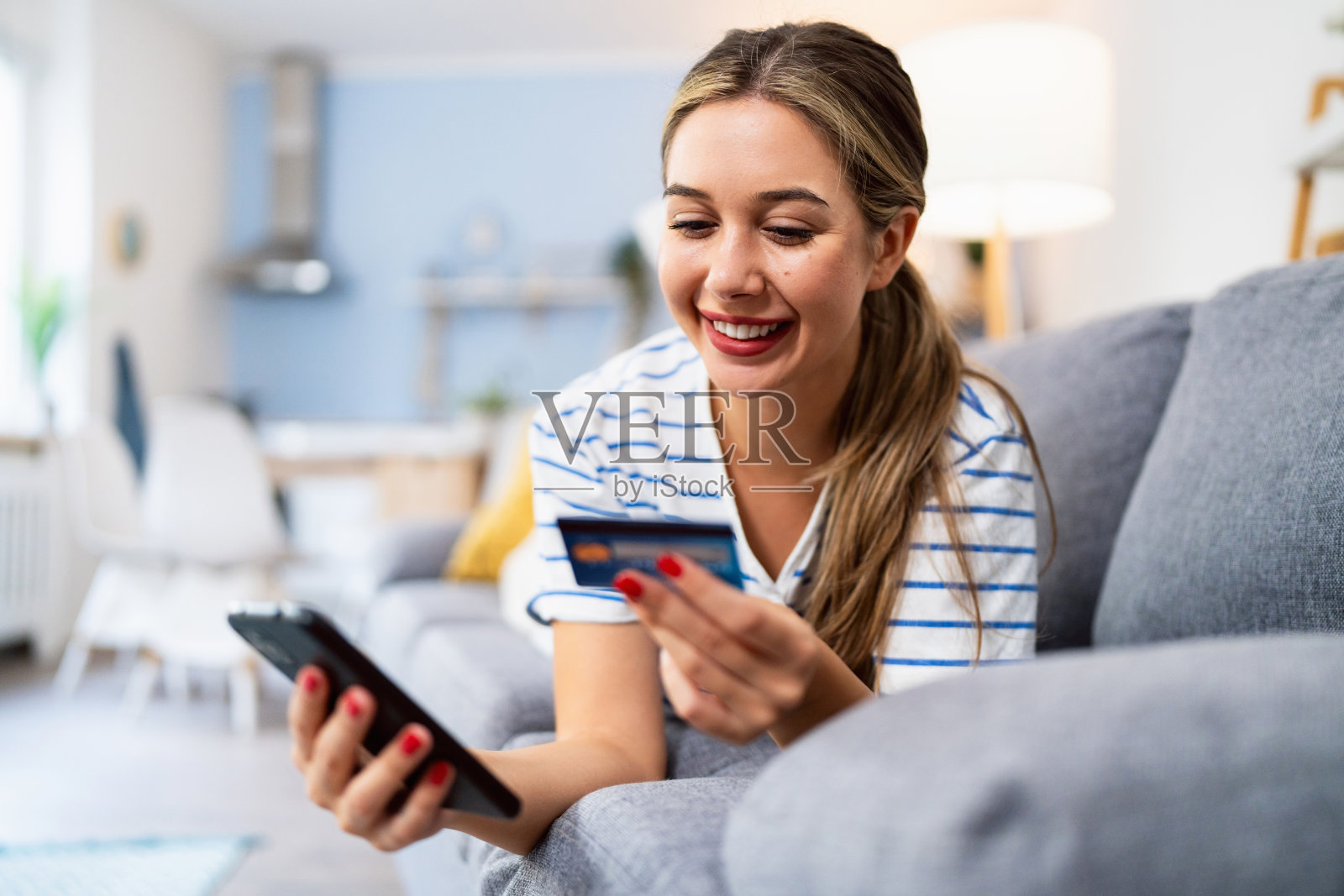 年轻的白人女性在沙发上放松，输入信用卡信息，进行在线购物。照片摄影图片