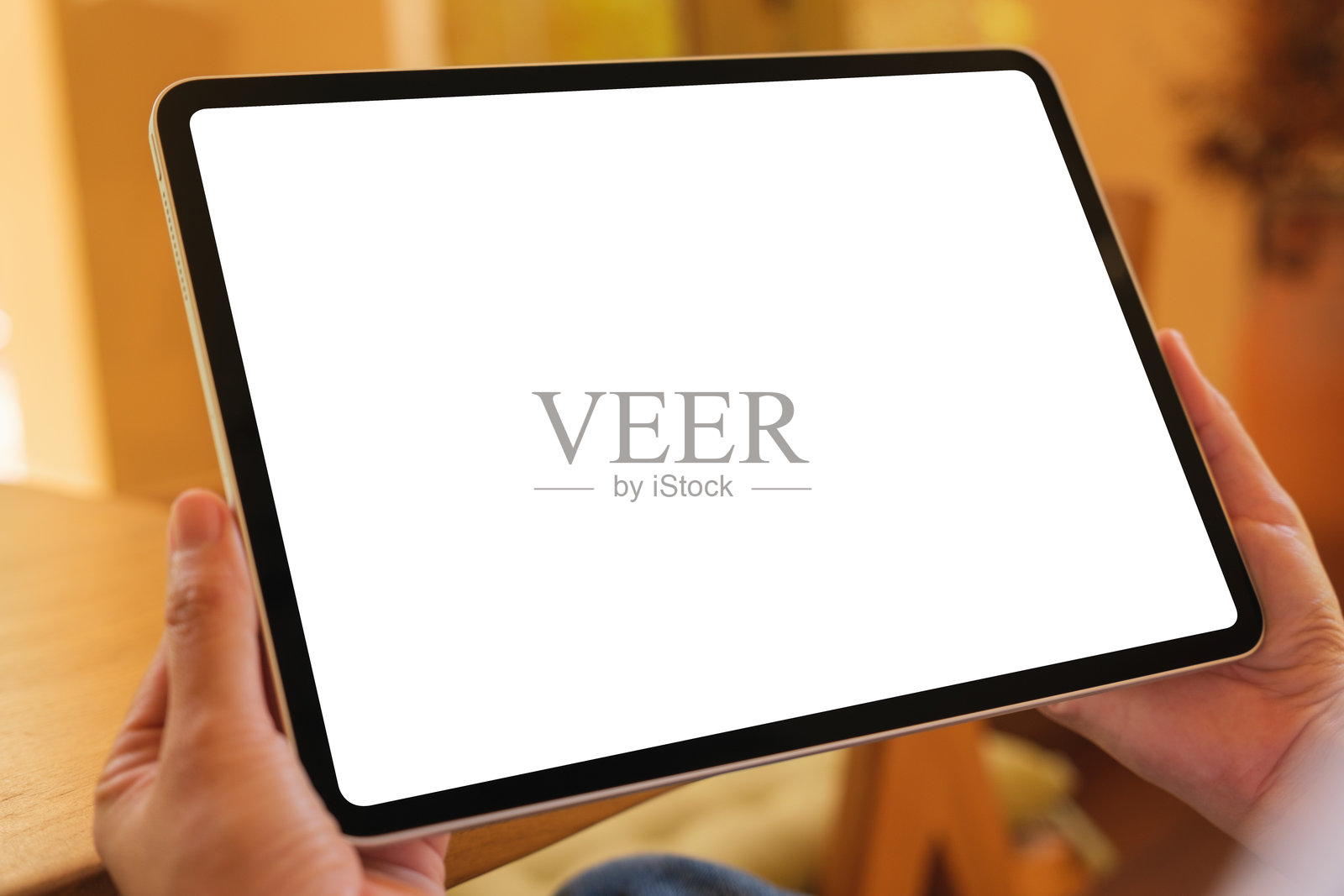 一位女性在家中手持数字平板，桌面屏幕为空白的模拟图像照片摄影图片