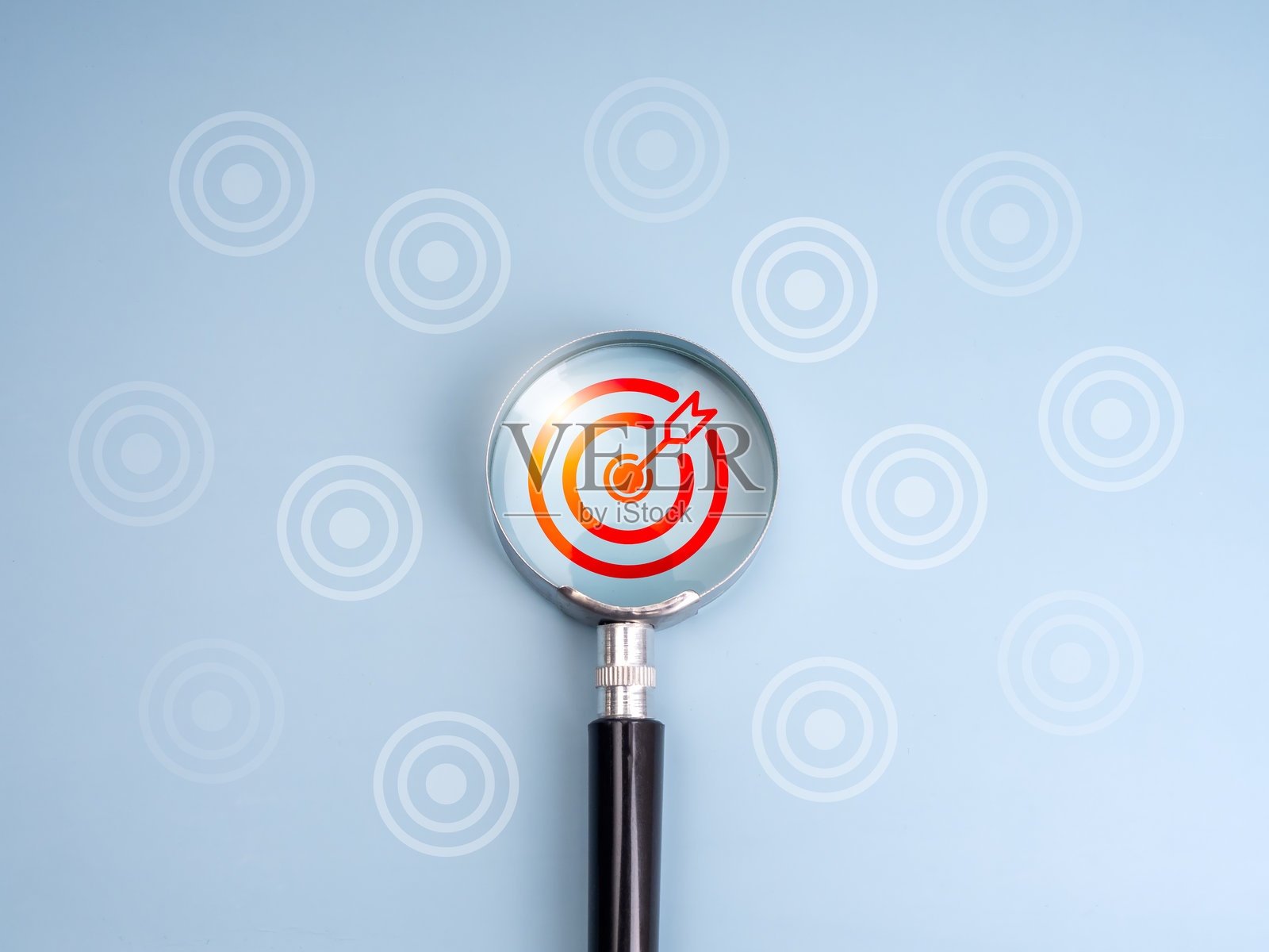 商业趋势和目标，正确的寻找目标，寻找真正的目标概念。红色靶心图标通过放大镜镜头聚焦在浅蓝色背景上的白色飞镖板周围。照片摄影图片