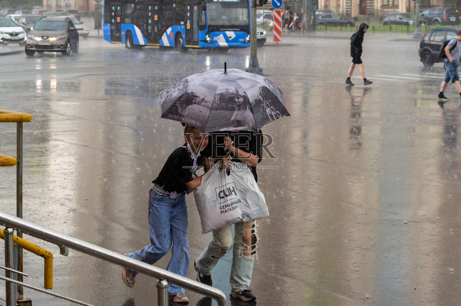 女人和女孩在雨中躲在伞下。女孩笑着，看起来很开心。照片摄影图片