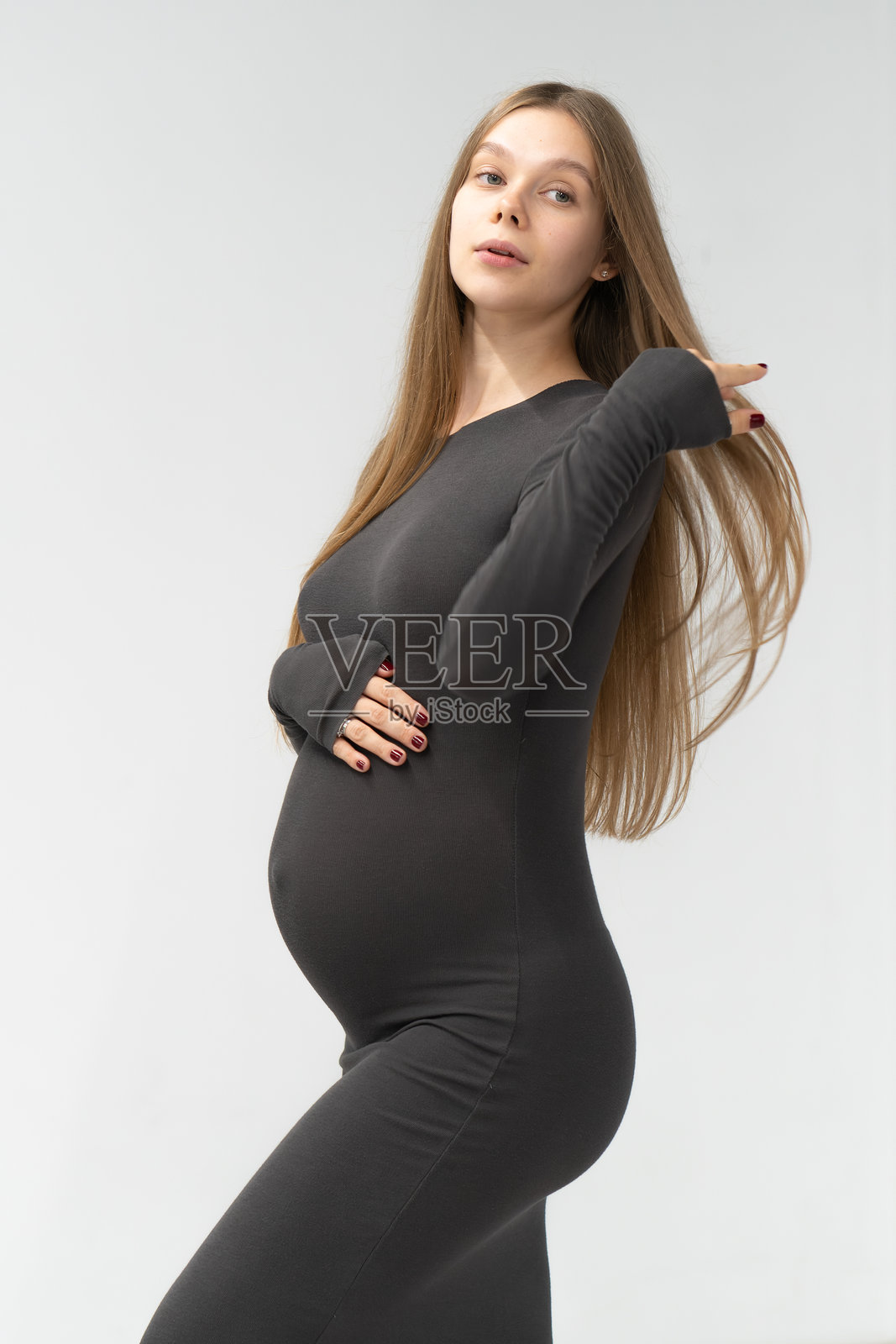 期待中的女性母亲，穿着黑色连衣裙，背景为怀孕的肚子，展现积极的情绪。照片摄影图片