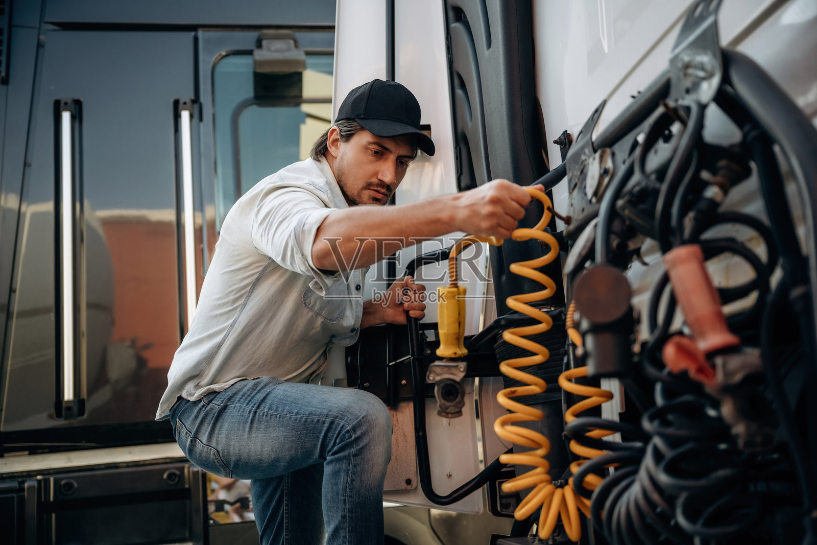 在户外，卡车司机靠近运输，正在处理电缆的安装和修理。照片摄影图片