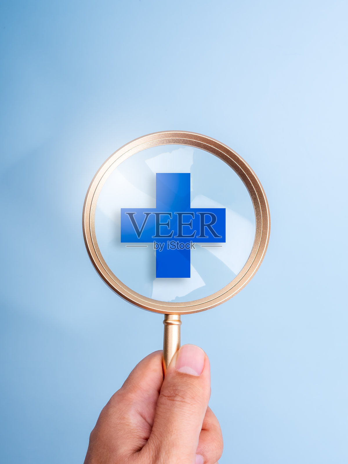 在线医疗服务搜索、健康计划、医疗保险概念：蓝色背景上手持放大镜观察医疗符号，竖版风格照片摄影图片