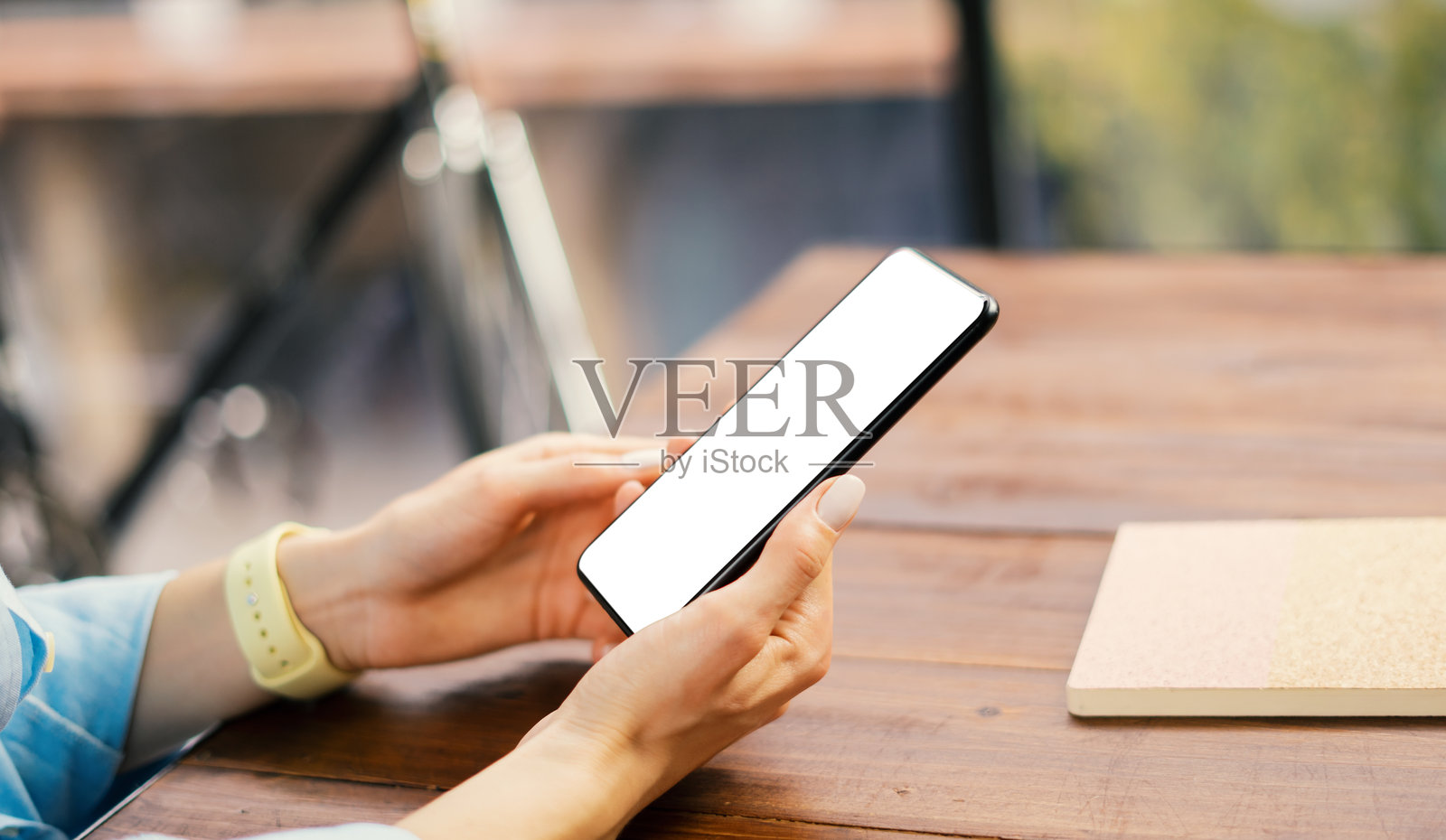 一位女性在木桌上使用带有空白屏幕的智能手机的模型图像照片摄影图片