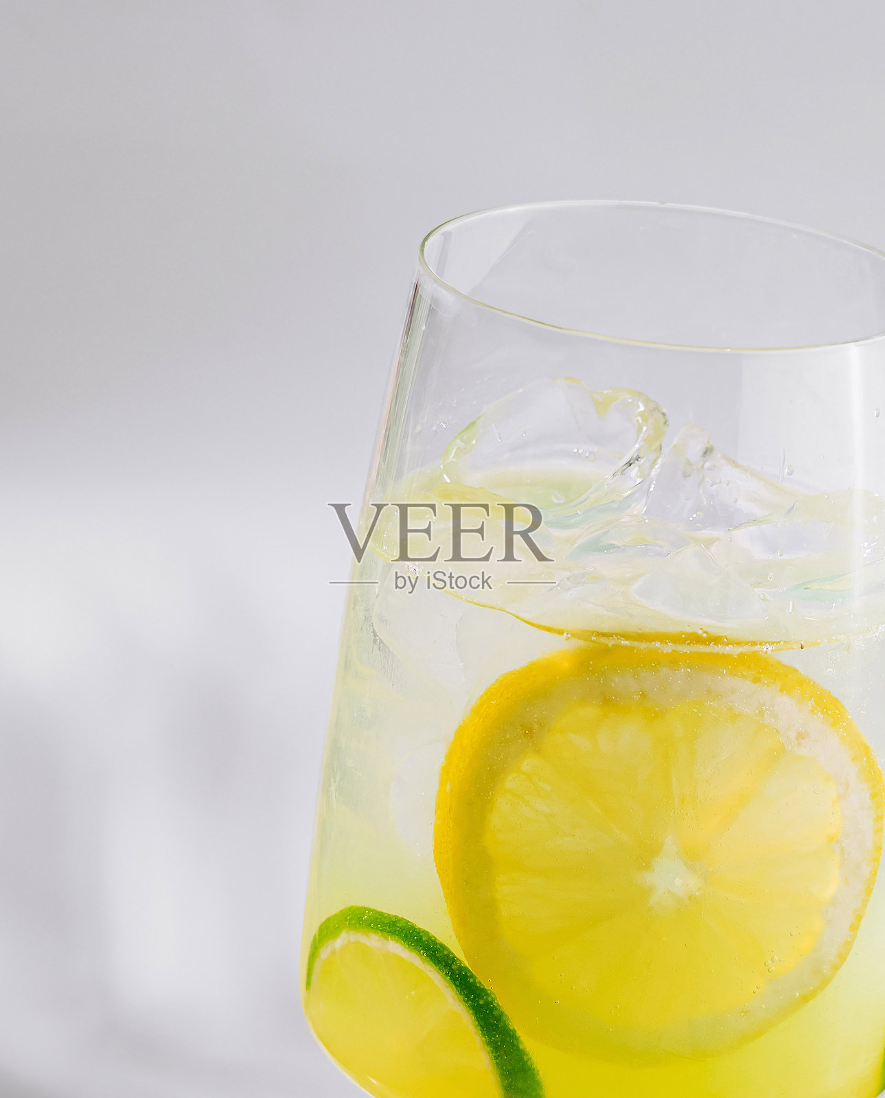 清爽的柠檬水，配有冰块、柠檬和青柠片，享受阳光。照片摄影图片