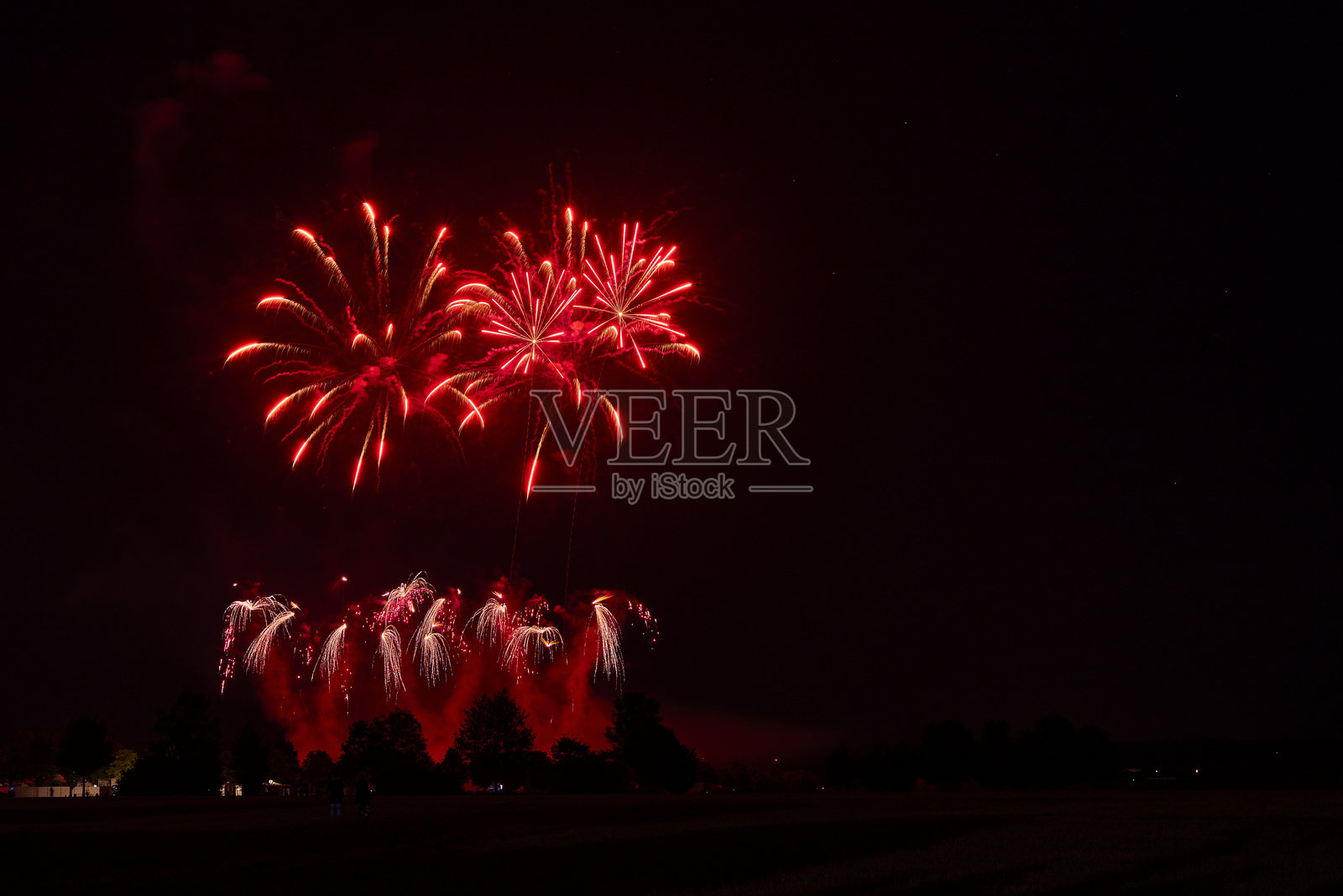 烟花在夜空中绽放，明亮的红色和粉色火花照亮黑暗，象征着新年庆祝活动的欢乐与喜庆。照片摄影图片