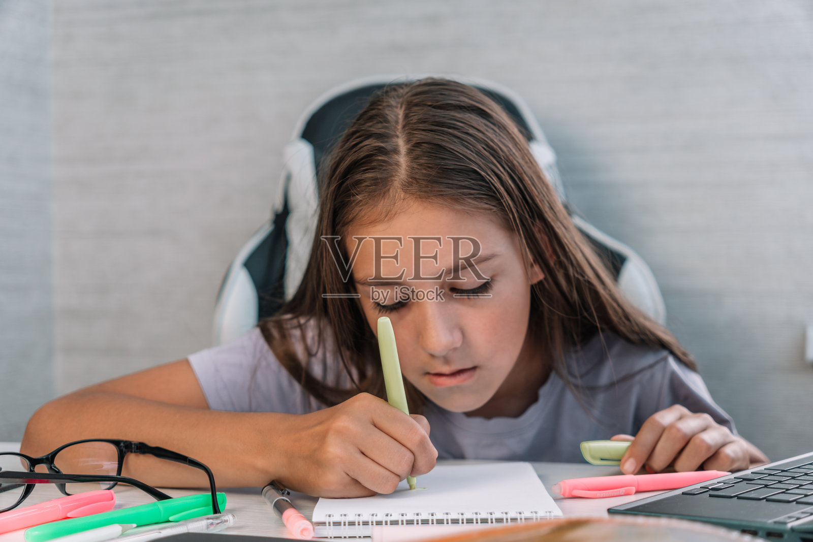 一个女学生在家里的桌子上做作业。漂亮的少女正在画画。照片摄影图片