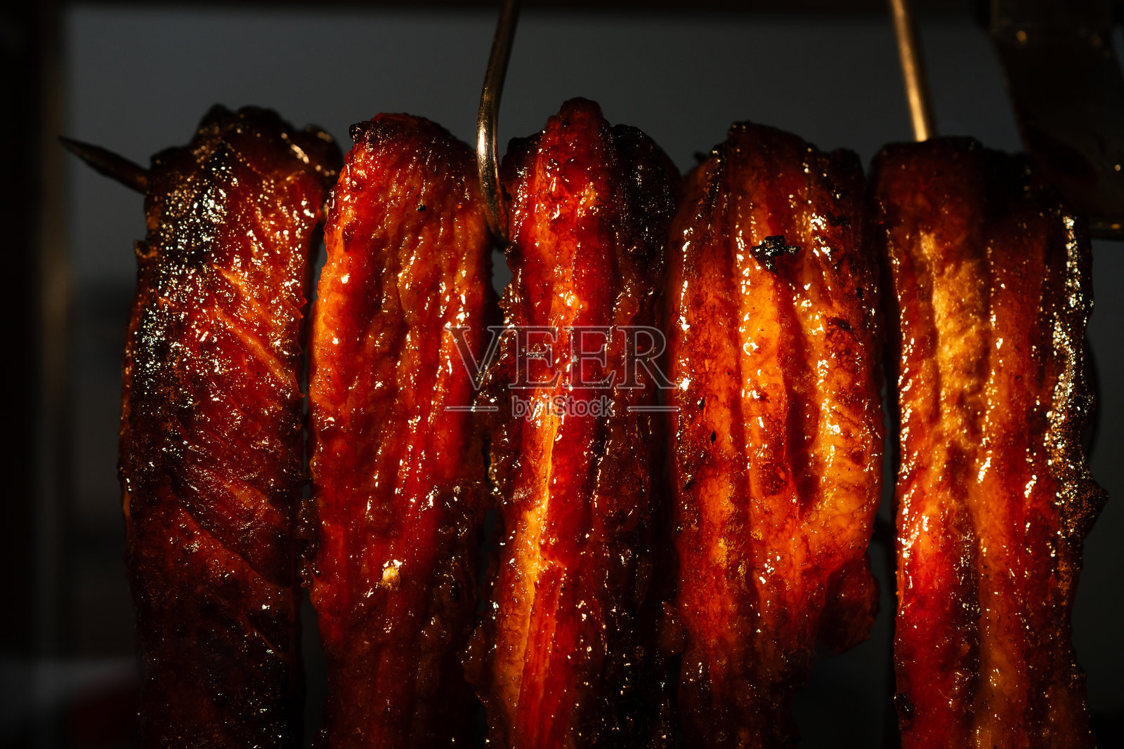 店前悬挂的蜜汁烤猪肉特写。照片摄影图片