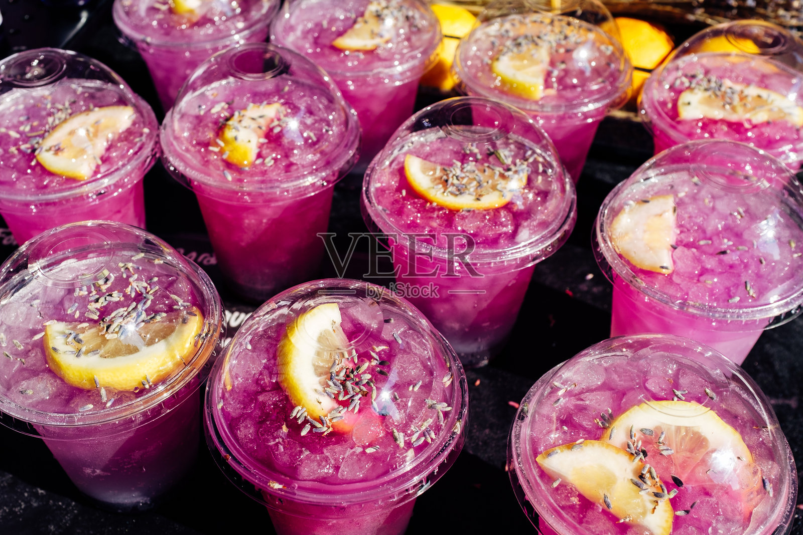 清新的薰衣草柠檬水，配有柠檬片和冰块，在夏季节庆中用塑料杯盛装。照片摄影图片