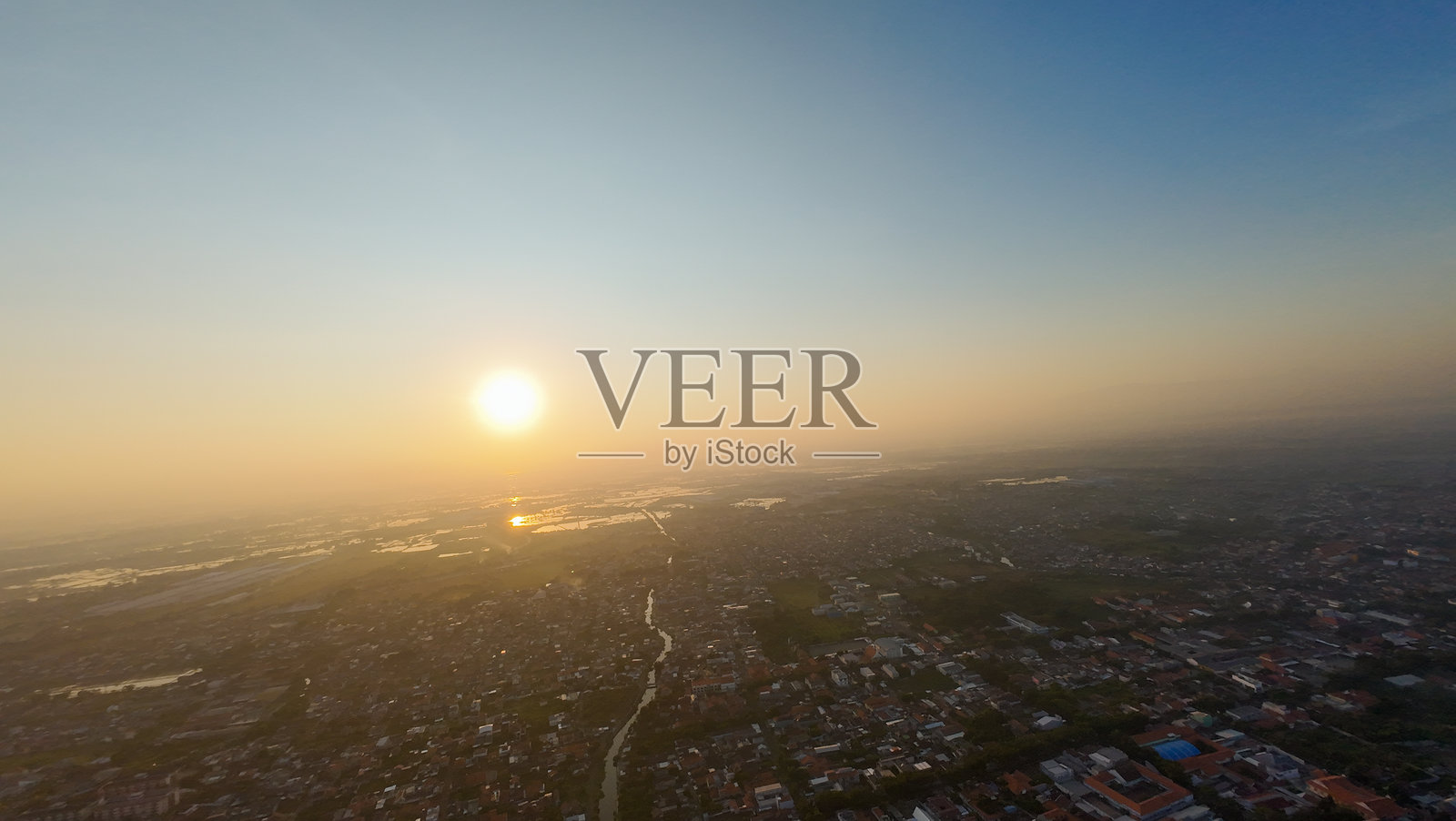 夕阳西下，城市的建筑被温暖的光辉笼罩。天空呈现出蓝色和橙色的交融，营造出宁静而祥和的氛围。照片摄影图片