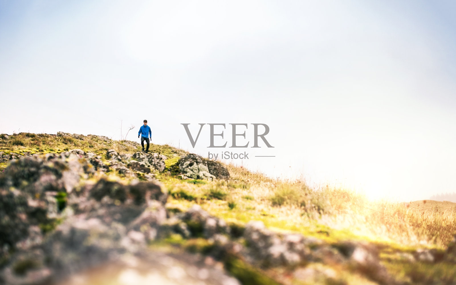 男性跑者在泥土跑道上向下跑。年轻人的晨跑训练。照片摄影图片