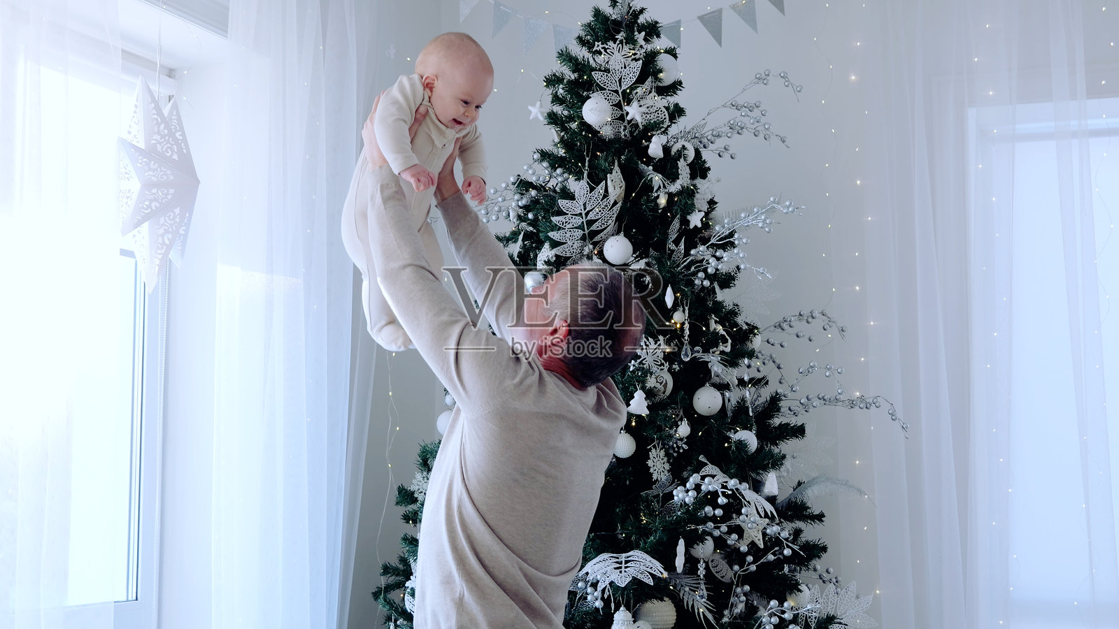 祖父在节日的圣诞树旁抱起他的孙女，珍惜他们一起度过的假日时光。圣诞节前的家庭日。与家人共度的新年夜。照片摄影图片