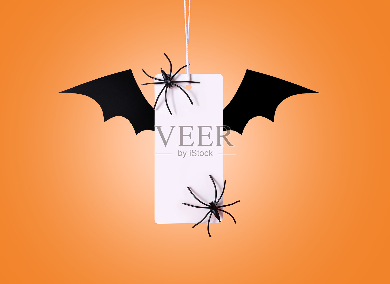 橙色背景上的白色标签，带有蝙蝠翅膀。万圣节促销。万圣节概念。照片摄影图片