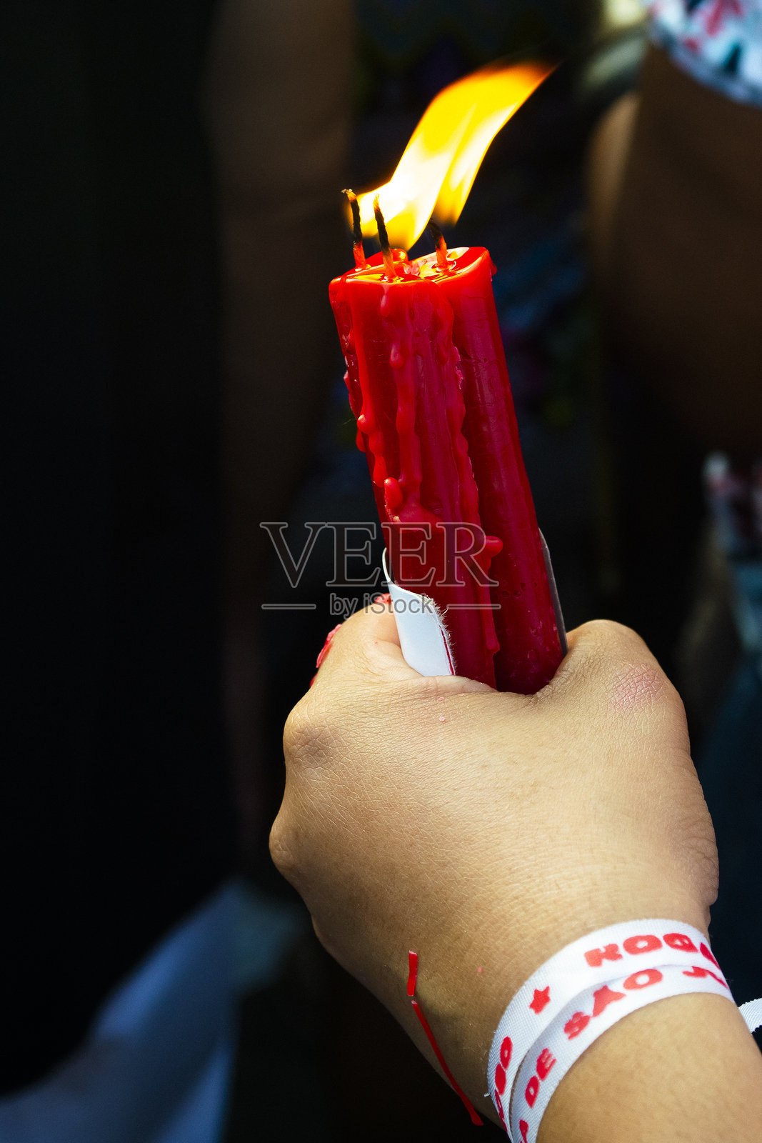 信徒的手在游行中举着一支红色蜡烛照片摄影图片