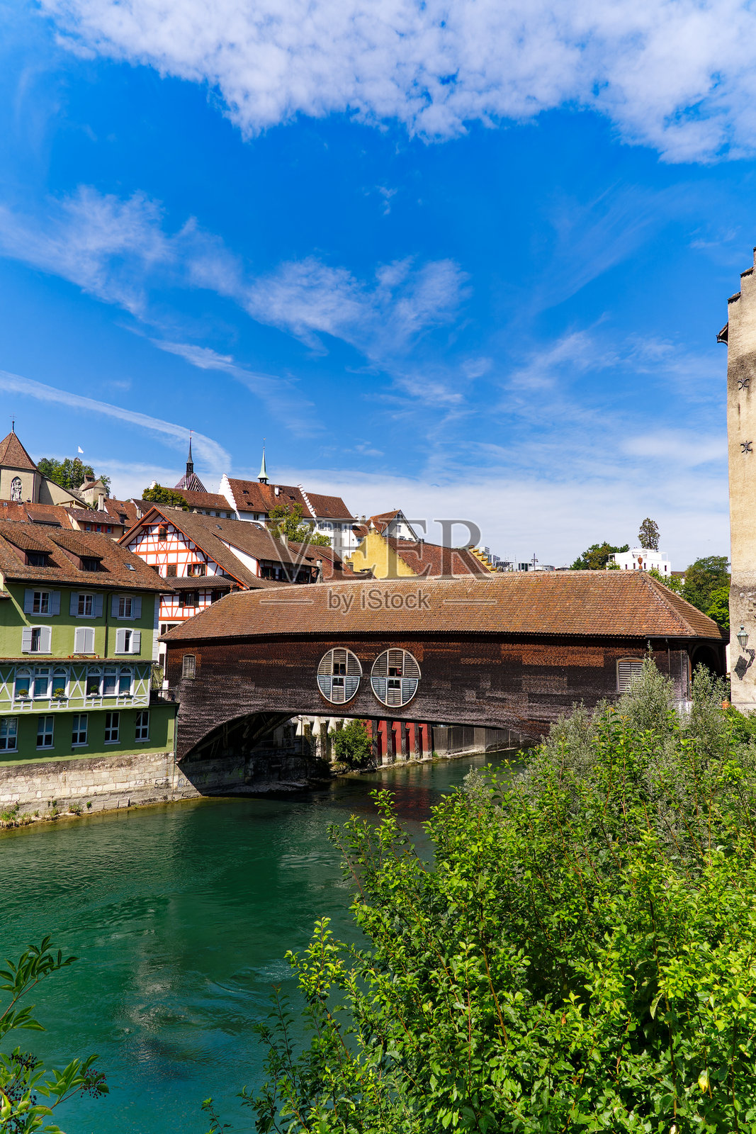瑞士巴登市的田园风光，木桥覆盖在利马特河上，背景是古老城镇的城市景观。照片摄影图片