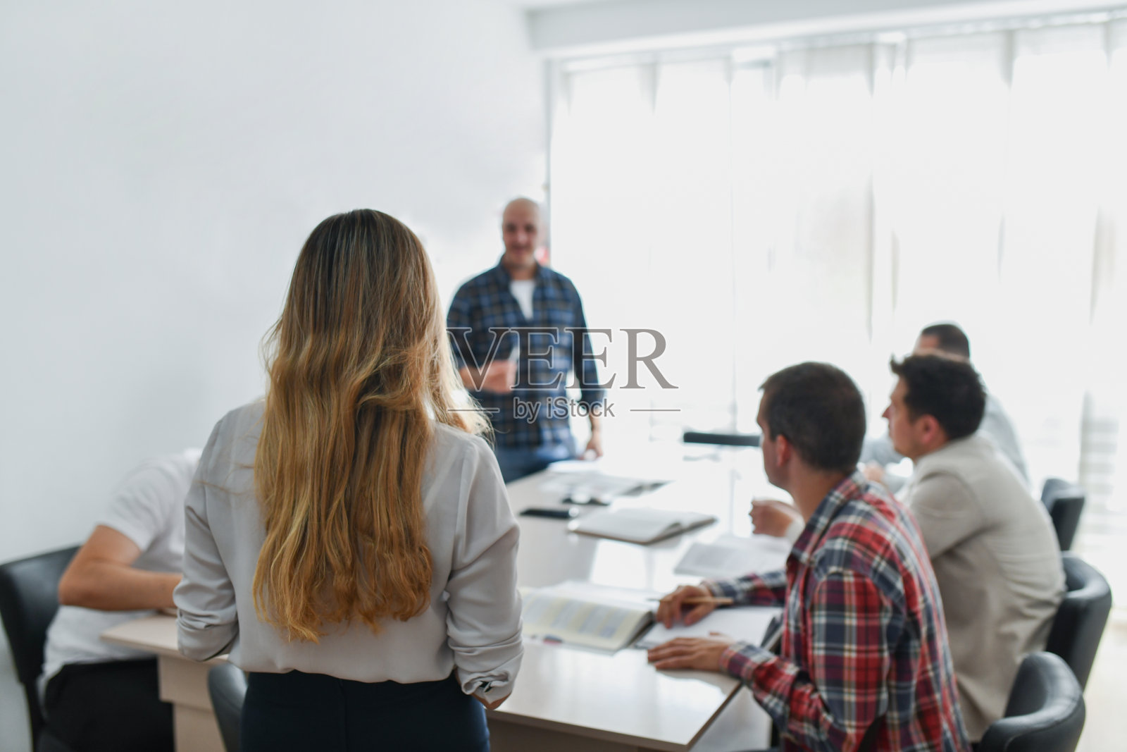 一群男性成年人在德语夜校集思广益，女性老师在认真倾听。照片摄影图片