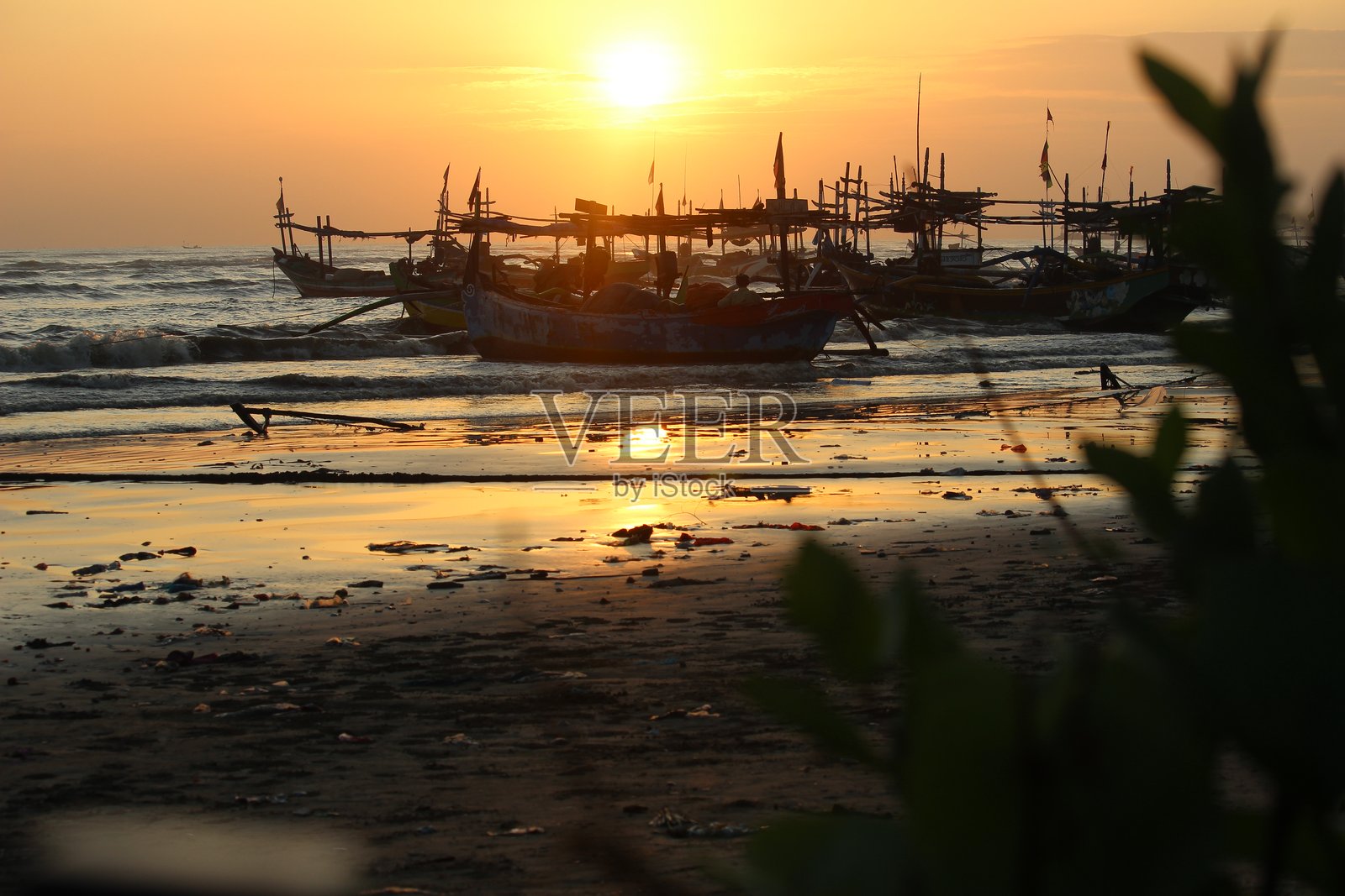 日落时分停靠在海滩上的木船照片摄影图片