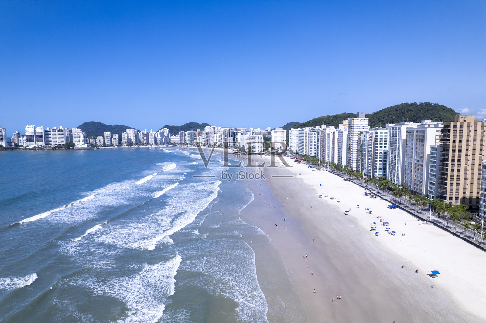 圣保罗瓜鲁雅的皮坦圭拉斯海滩鸟瞰图，阳光明媚，水面闪闪发光，高楼大厦林立。照片摄影图片