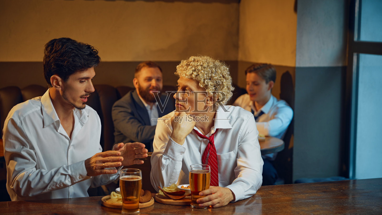 两名男士，作为同事在酒吧享受啤酒和小吃，同时深入进行富有思考的对话。照片摄影图片