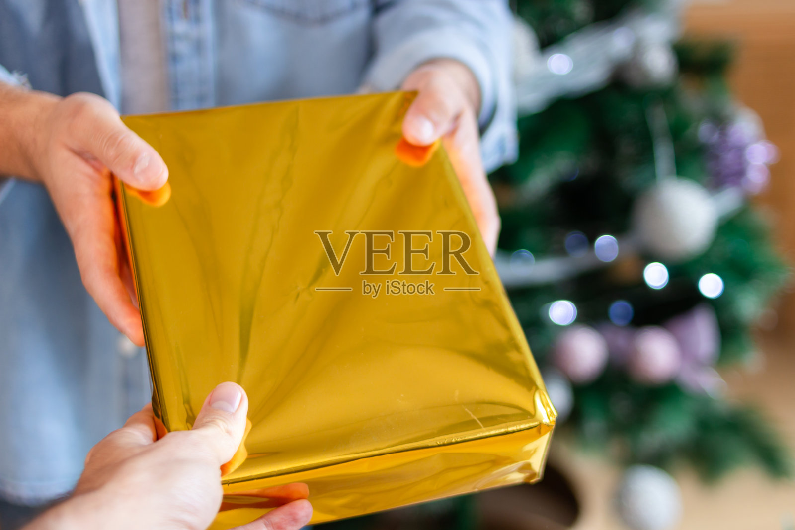 在圣诞树前赠送金色圣诞礼物照片摄影图片