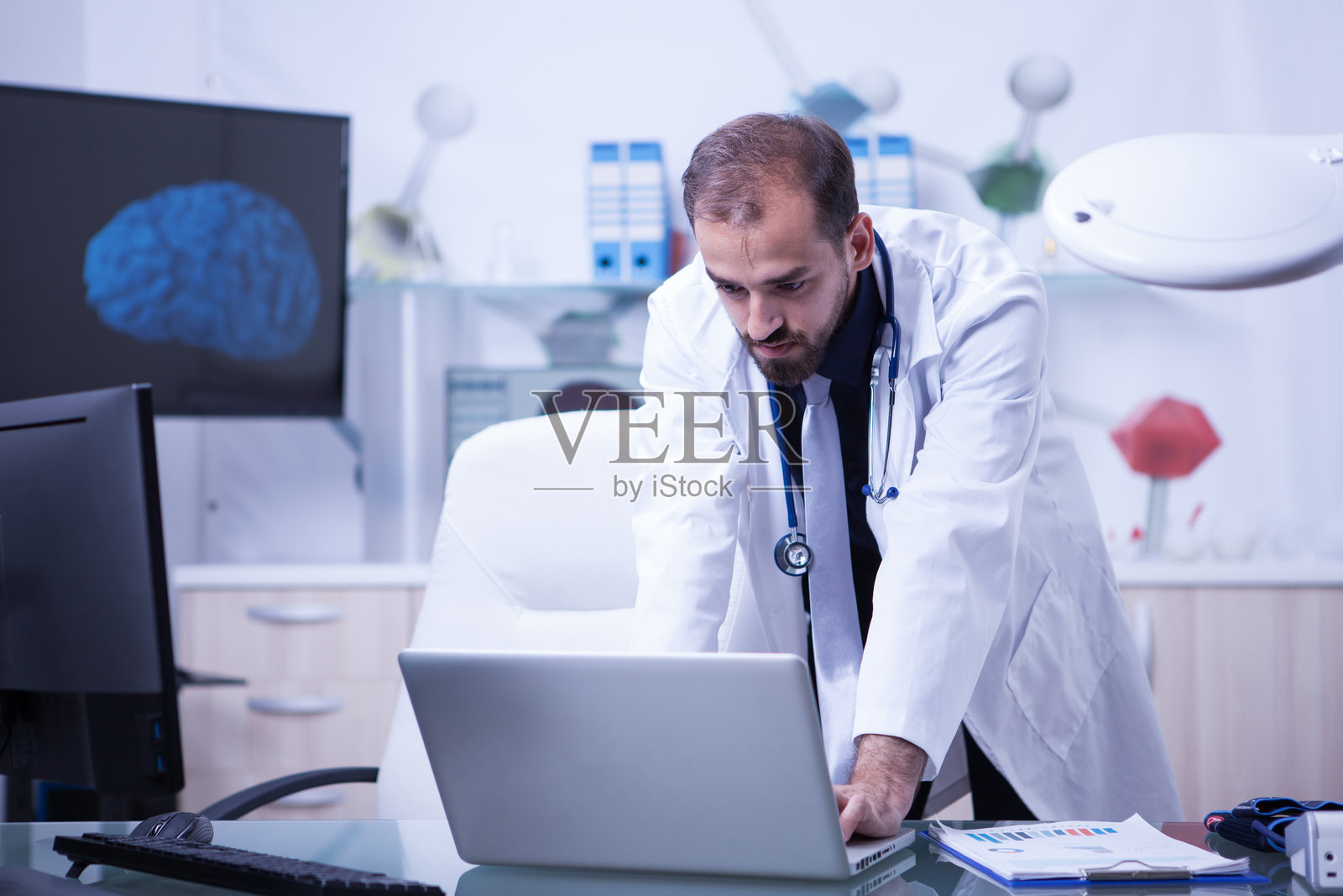 医生在笔记本电脑上工作，查看患者的治疗情况照片摄影图片