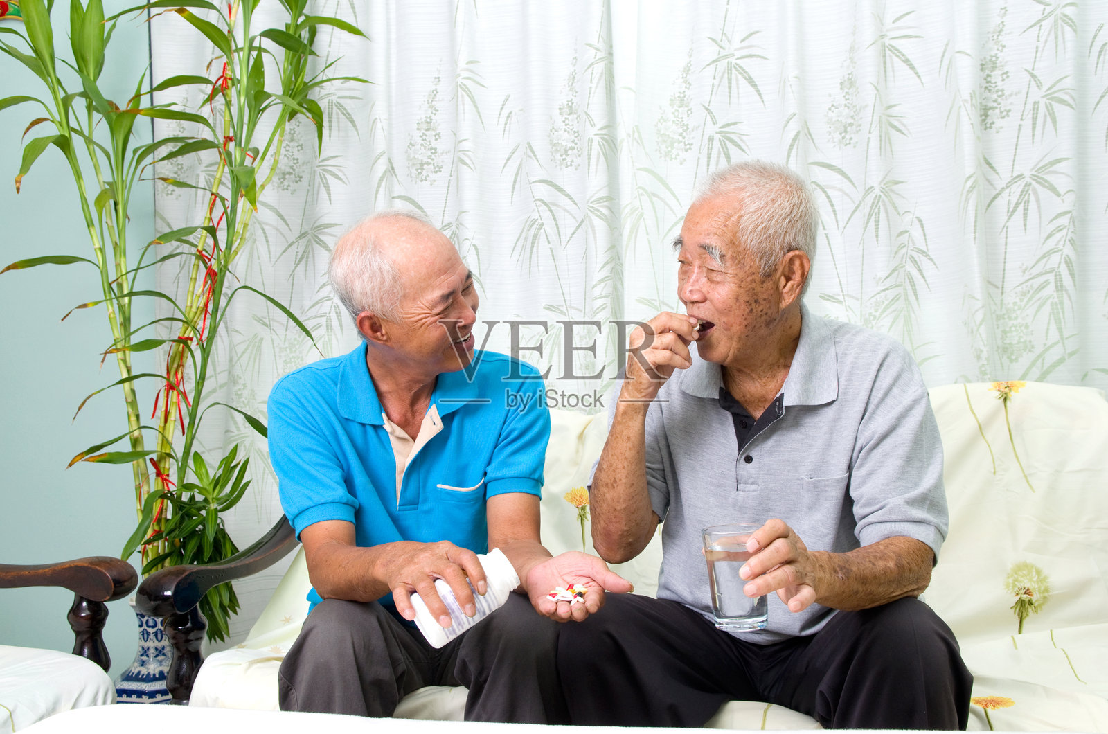 男人在家给男性朋友喂药照片摄影图片