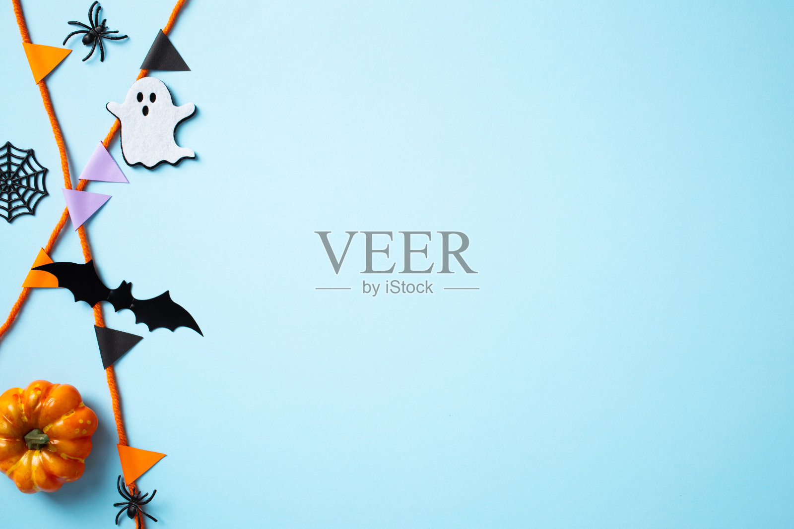 万圣节快乐的节日概念。蓝色背景上的扁平布局，包含彩旗、南瓜、鬼魂、蝙蝠和蜘蛛。恐怖的万圣节横幅设计。照片摄影图片