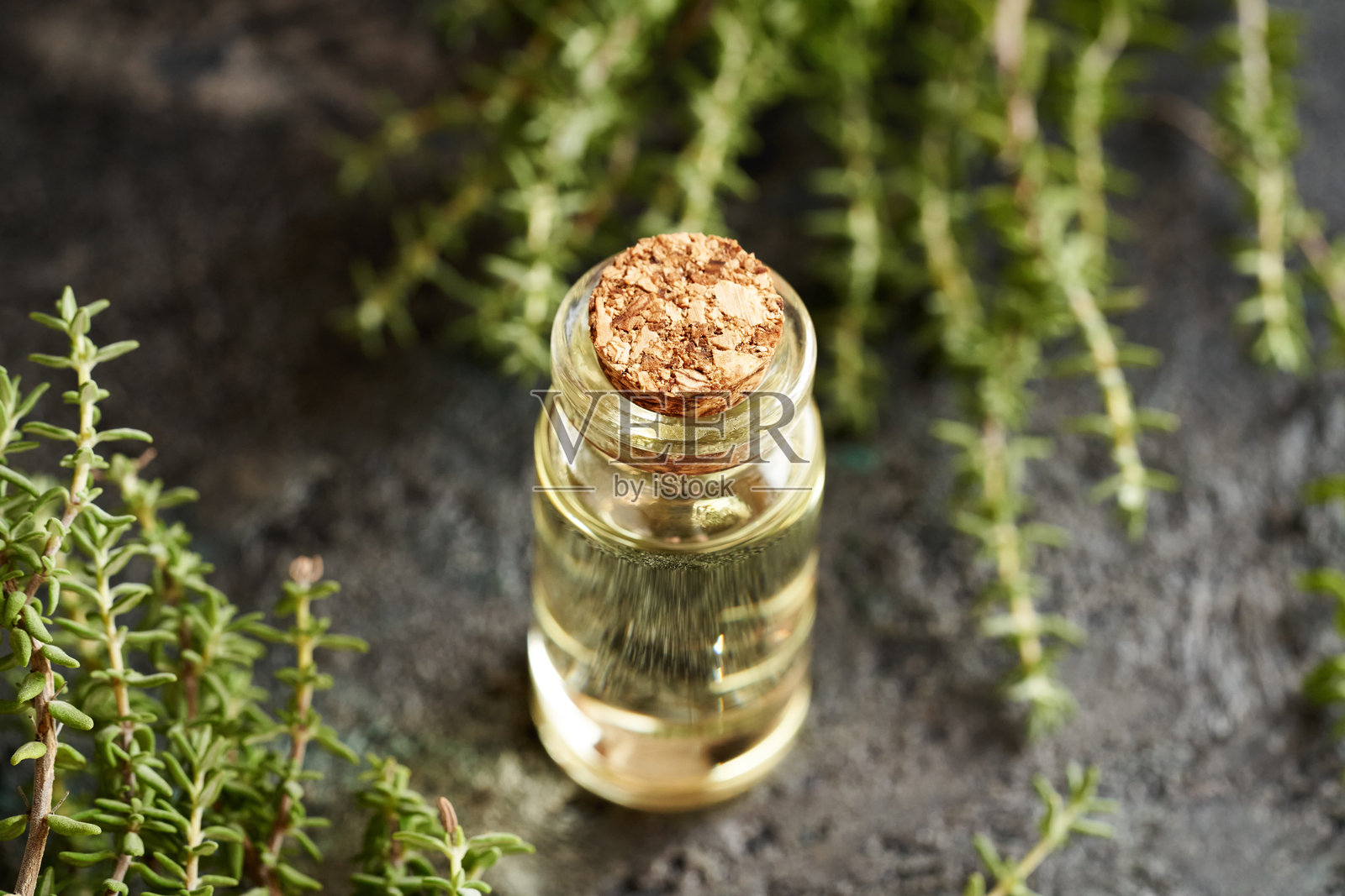 一瓶透明的香薰精油，里面有新鲜的百里香叶照片摄影图片