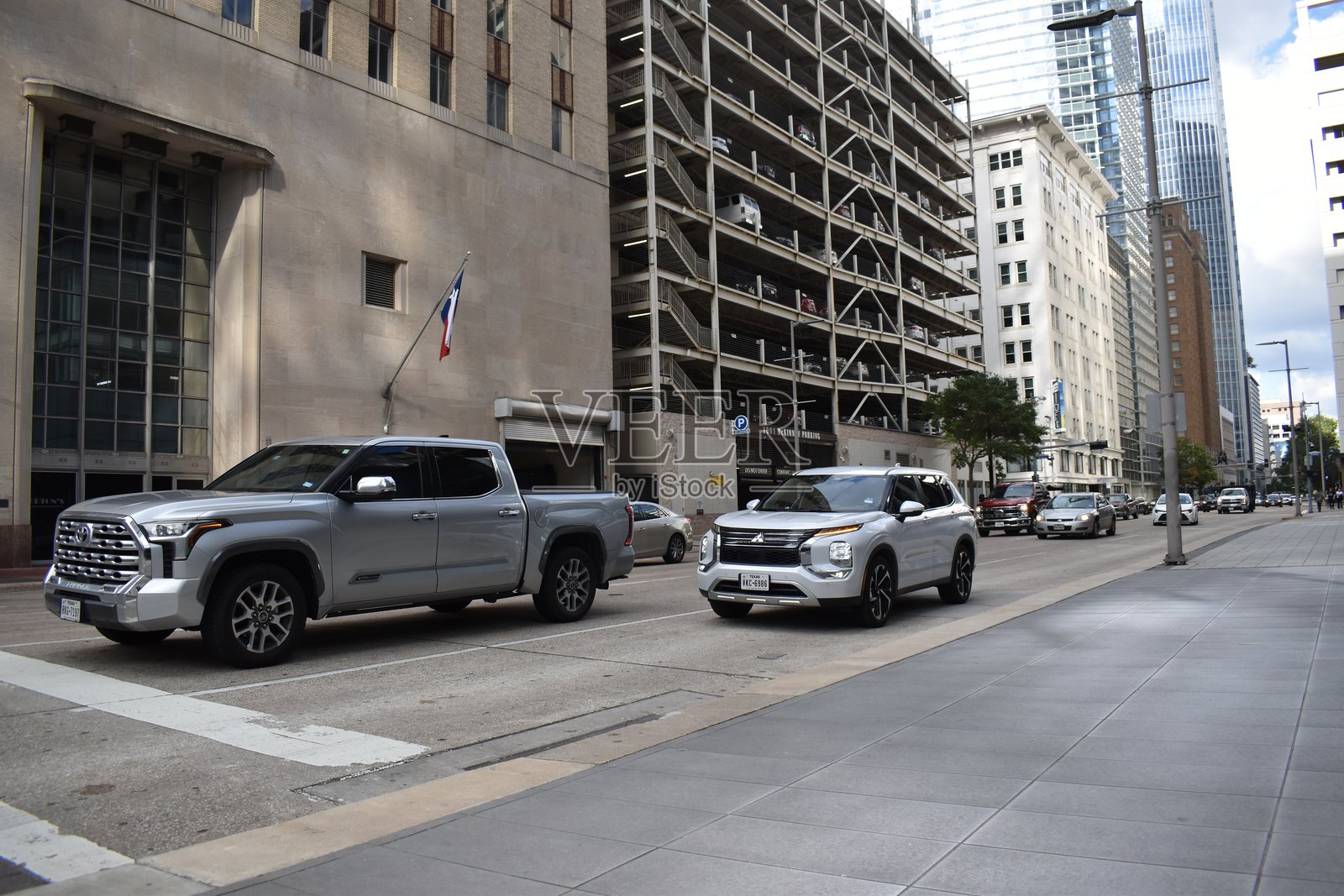 一辆雪佛兰科罗拉多皮卡和一辆三菱欧蓝德在市中心金融区的交通中行驶。照片摄影图片