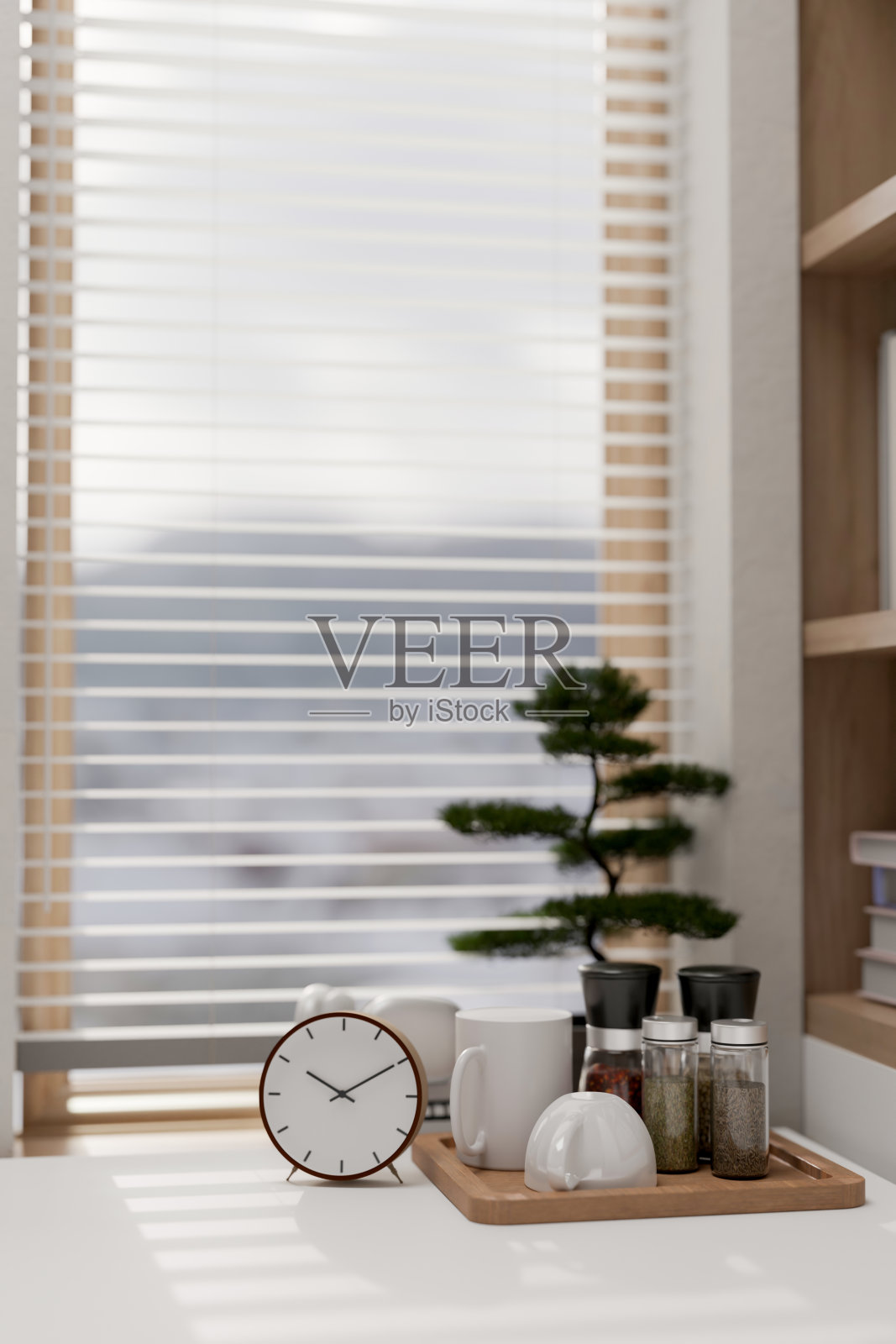 窗边的白色桌子上摆放着一个闹钟、一盆装饰植物和一个咖啡套装，放在托盘上。照片摄影图片