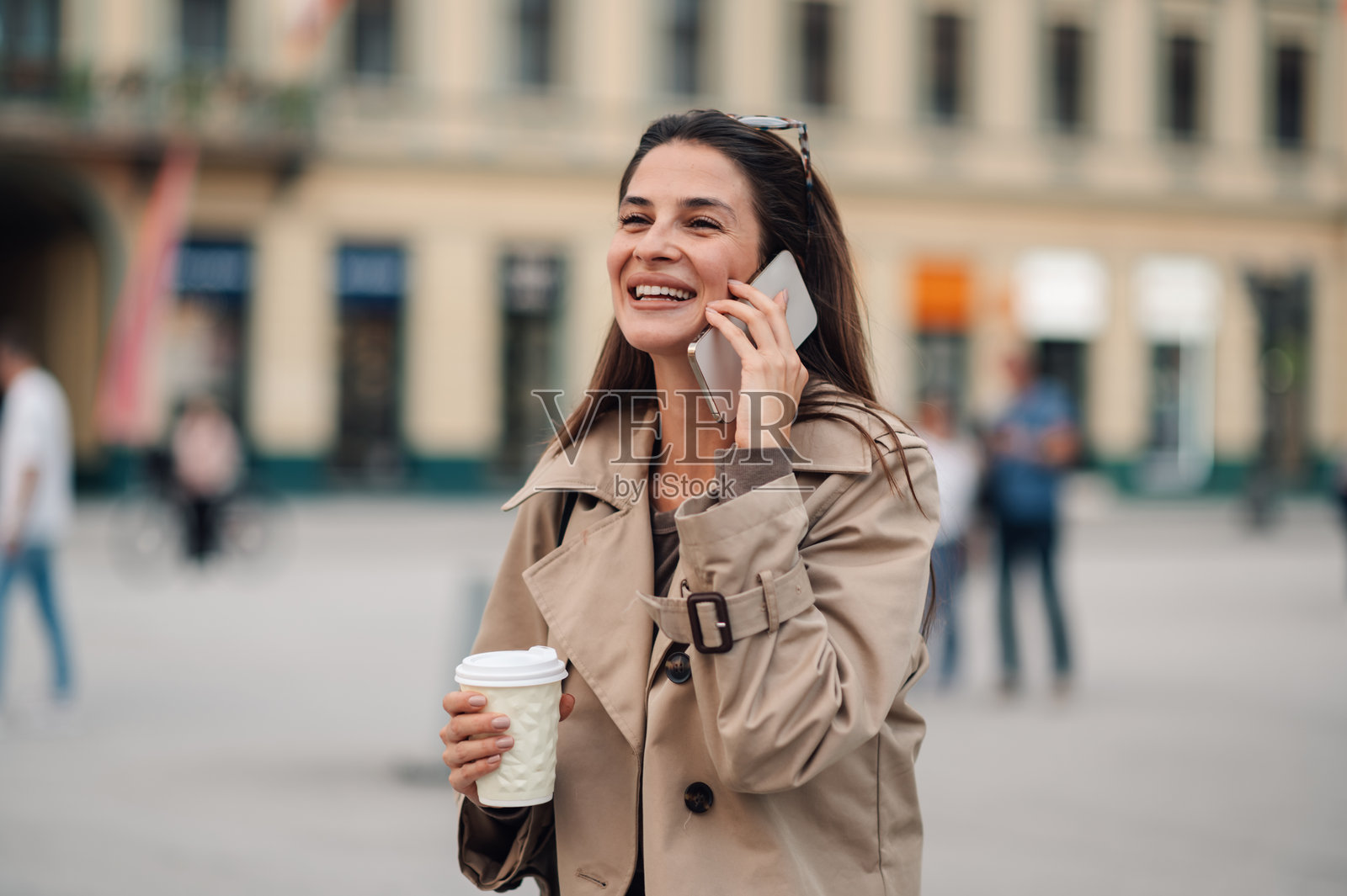 快乐的女人在城市里一边打电话一边喝咖啡照片摄影图片