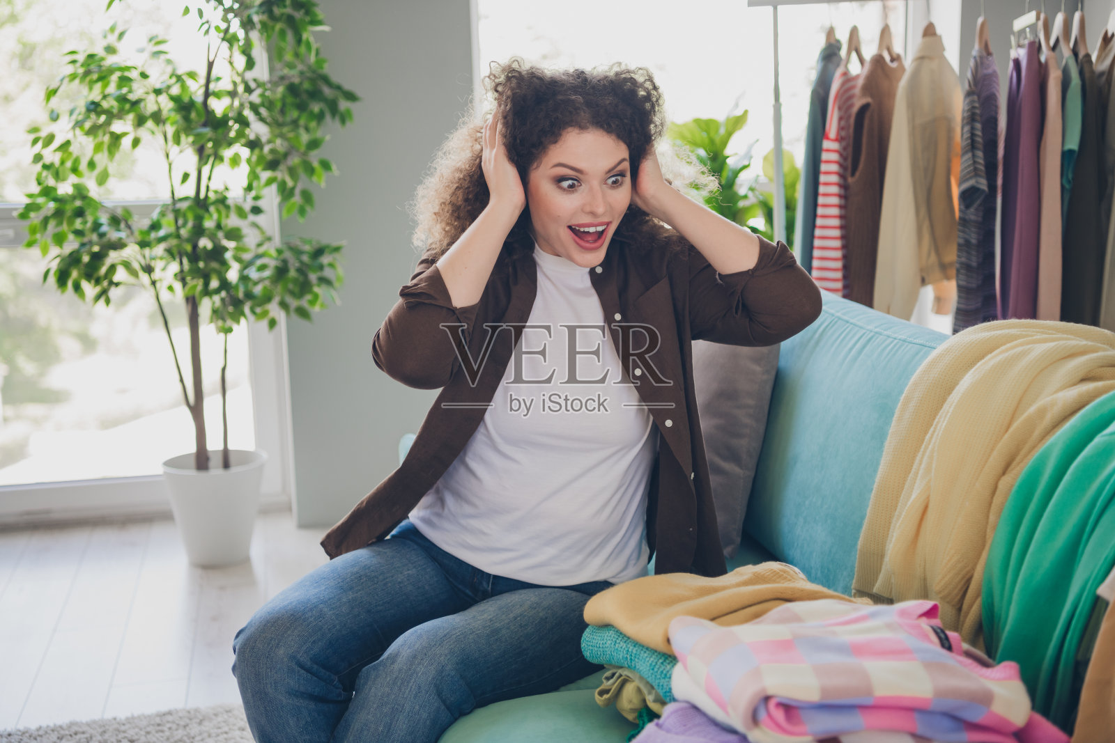 年轻女子在现代阁楼住宅沙发上欣赏新衣服的照片照片摄影图片