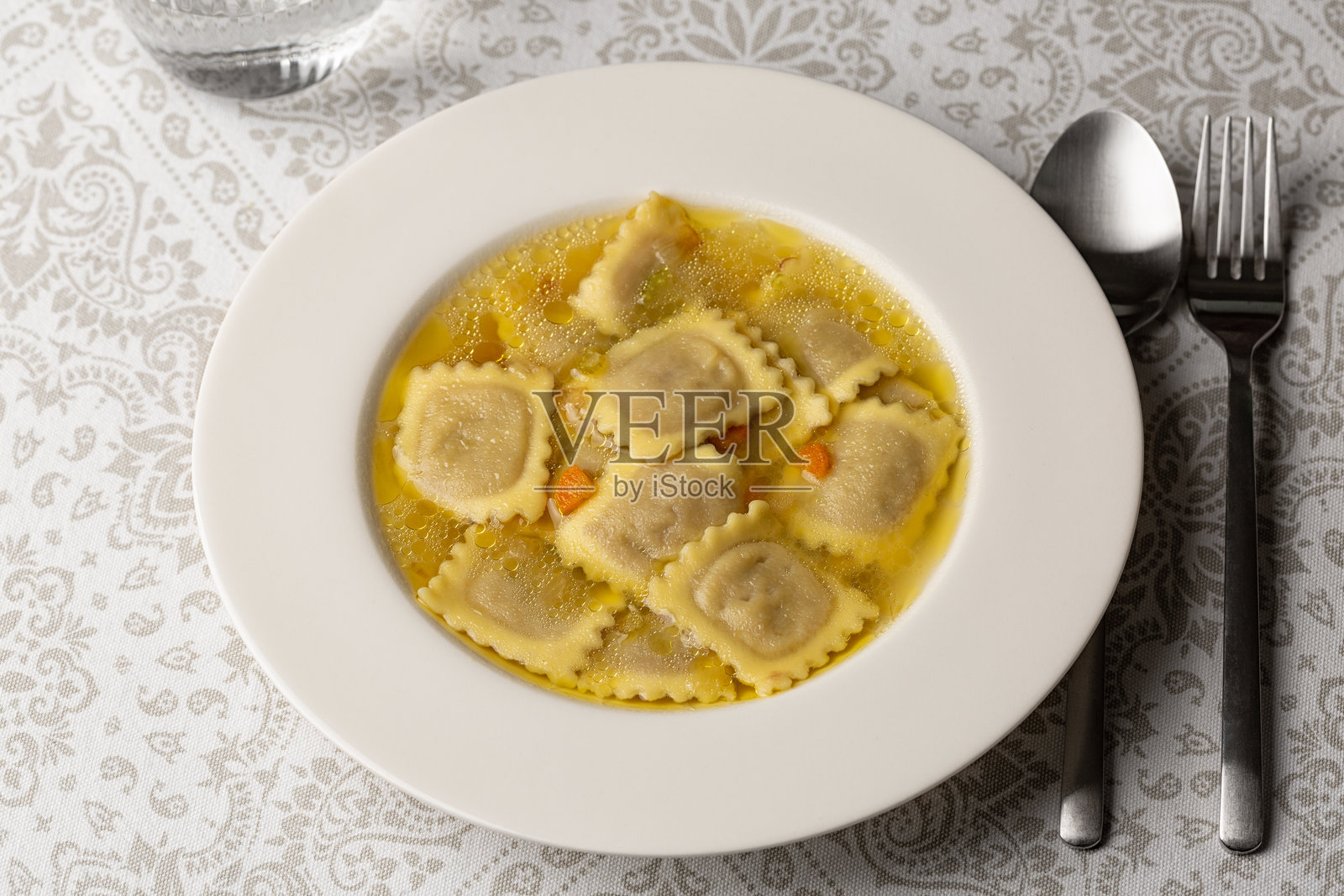 肉汤饺子。新鲜的意大利肉馅饺子，面团包裹肉馅，浸泡在蔬菜高汤中。照片摄影图片