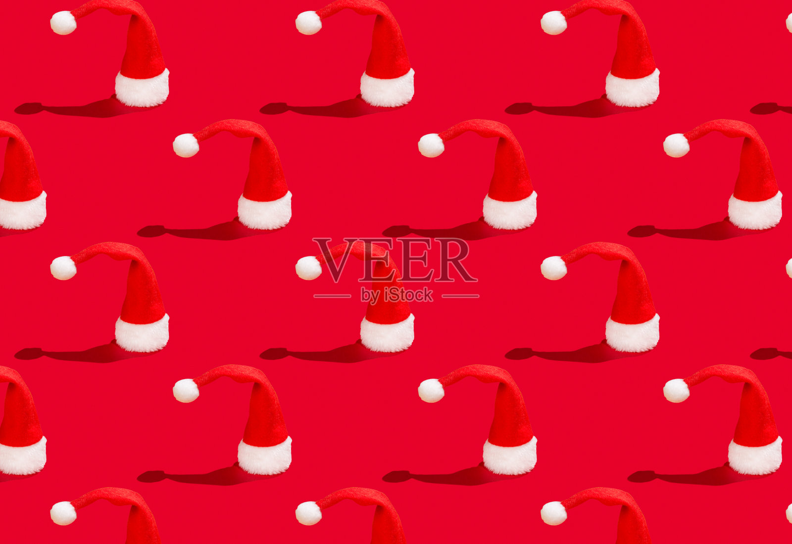 红色背景上的圣诞老人帽子。新年或圣诞节抽象图案照片摄影图片