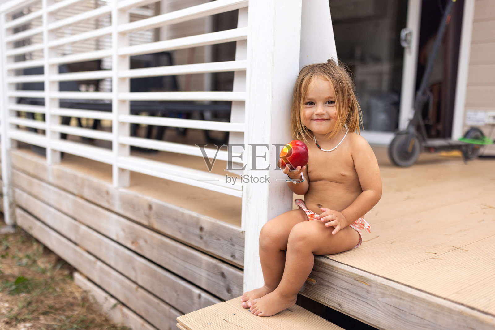 一个孩子在房子前面的台阶上吃苹果照片摄影图片
