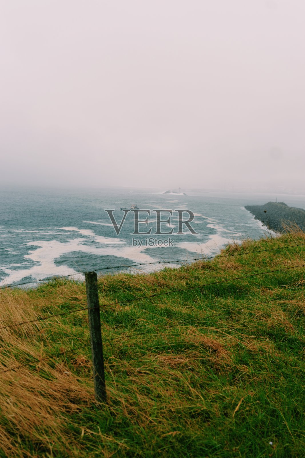 特塞拉岛海岸的雾气弥漫的悬崖与拍打的海浪照片摄影图片