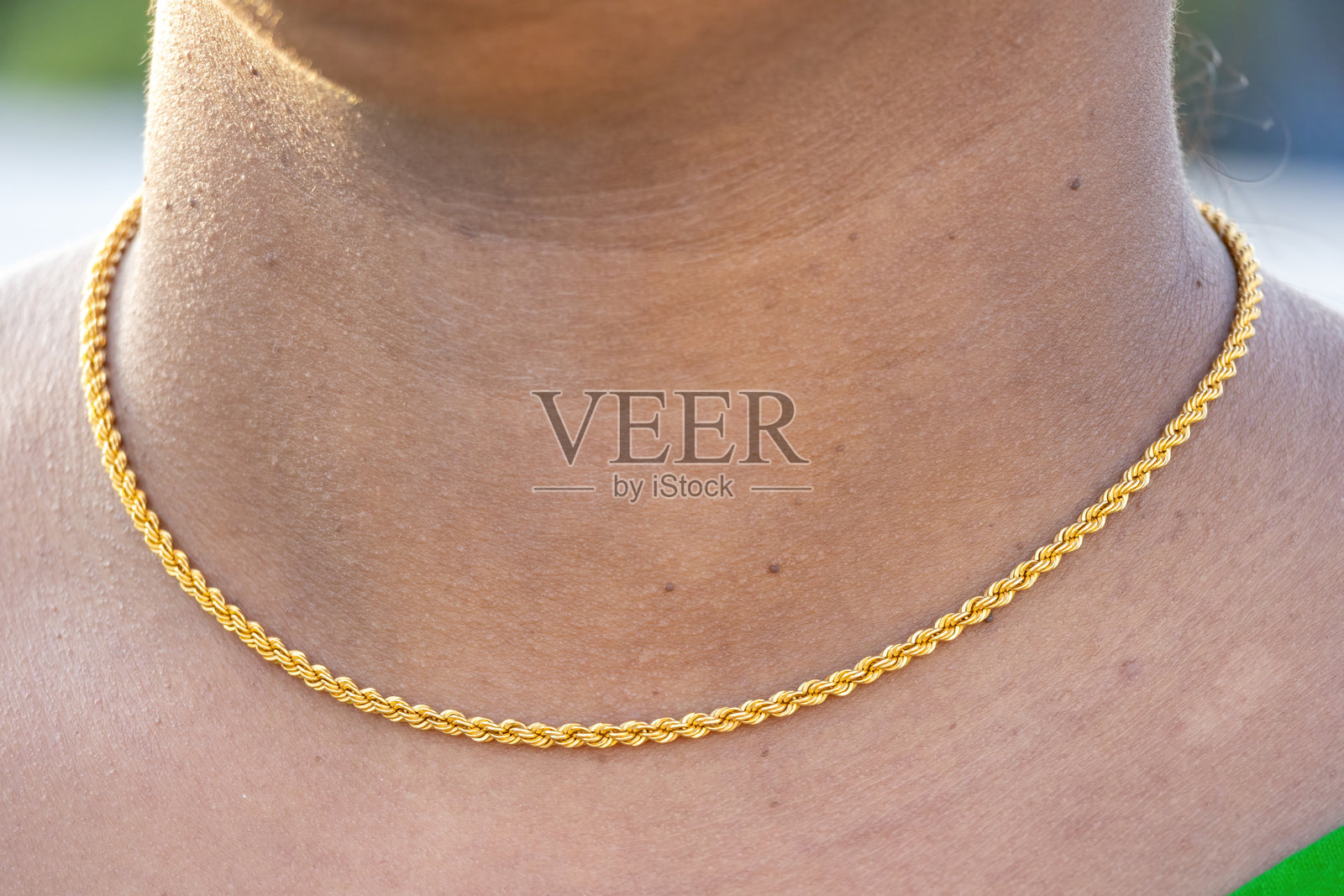 亚洲女性脖子上的金项链。年轻女士的金项链特写。一条金链子佩戴在女性的脖子上。照片摄影图片