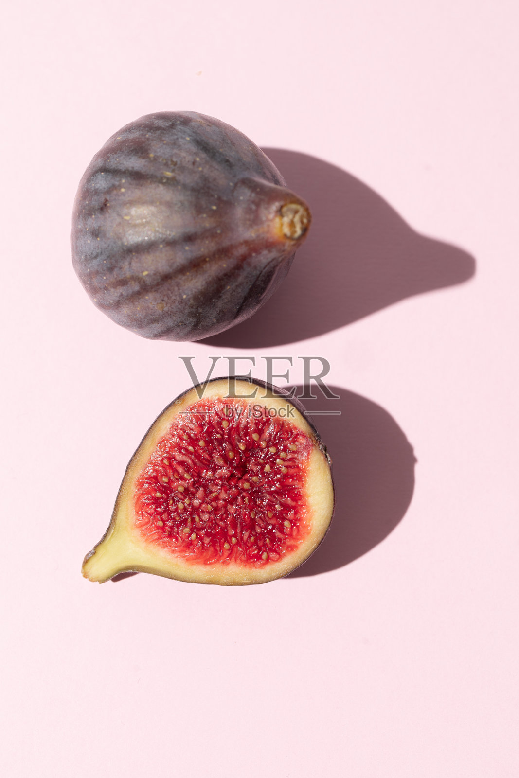 半个紫色无花果与一个完整的无花果放在粉色盘子上照片摄影图片
