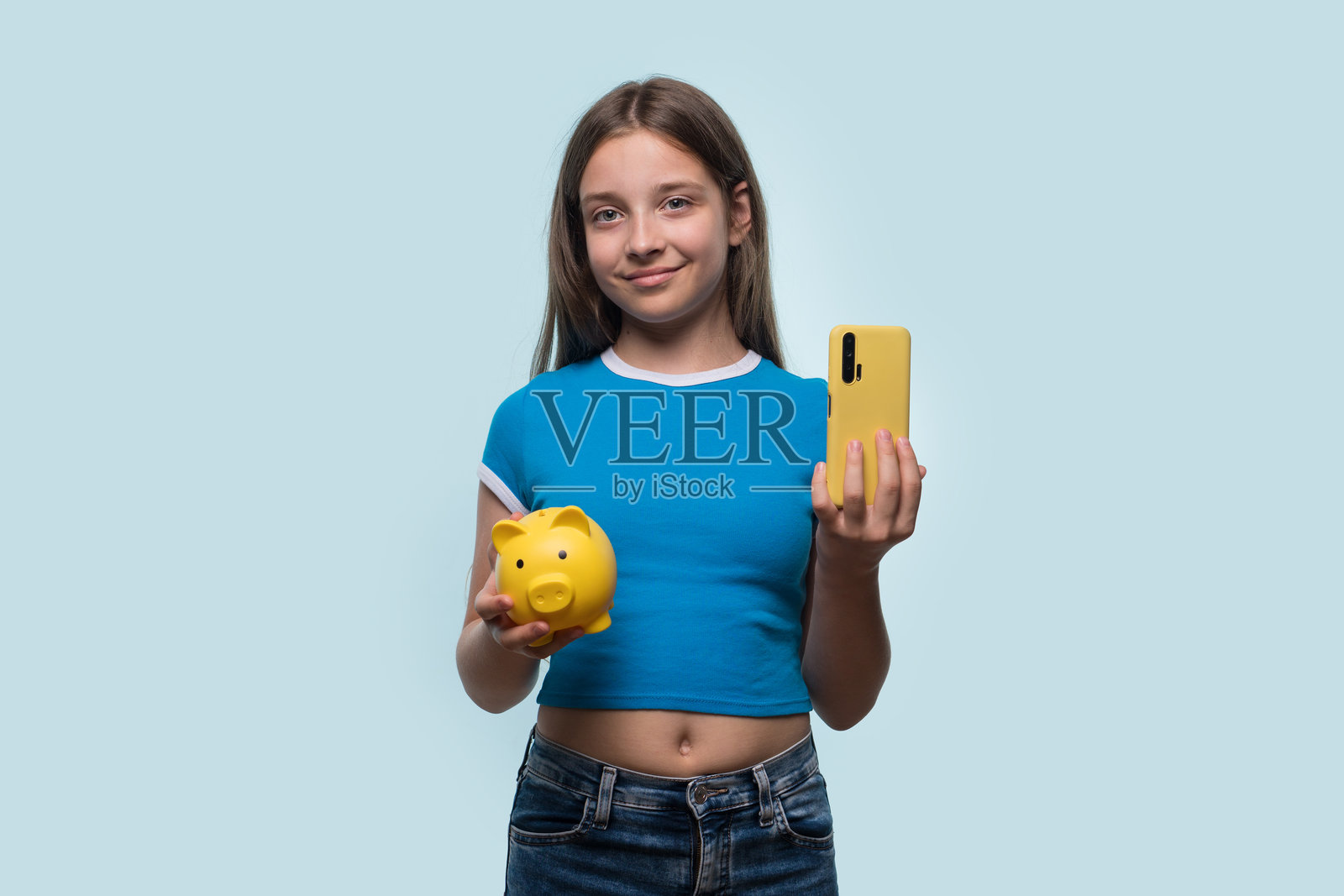 女孩手持黄色储蓄罐和智能手机照片摄影图片