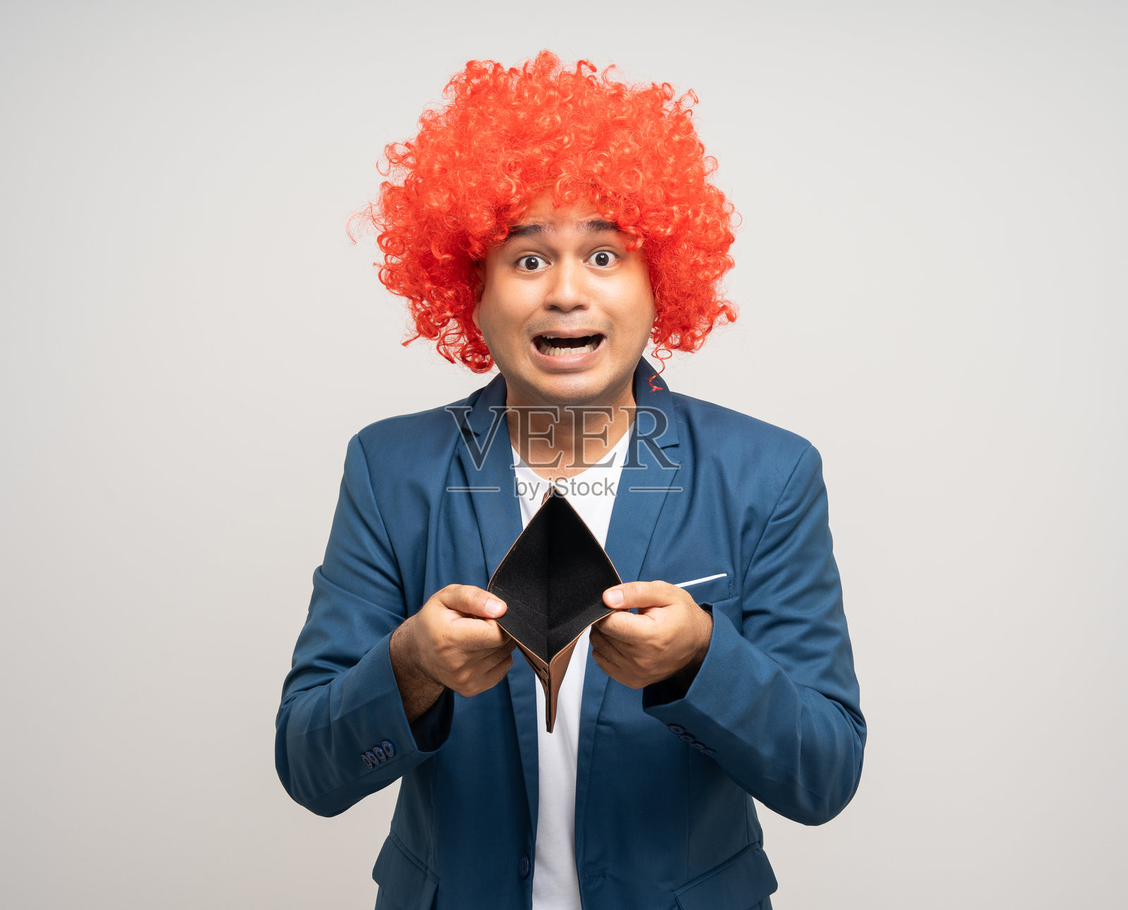 年轻的亚洲男子留着非洲卷发，手里拿着一个空钱包，翻过来却没有钱。照片摄影图片